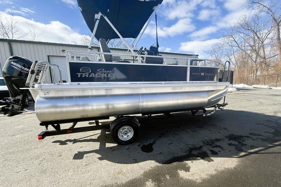 2026 Sun Tracker Bass Buggy 16 XL Select pontoon boat on trailer, outdoor setting.
