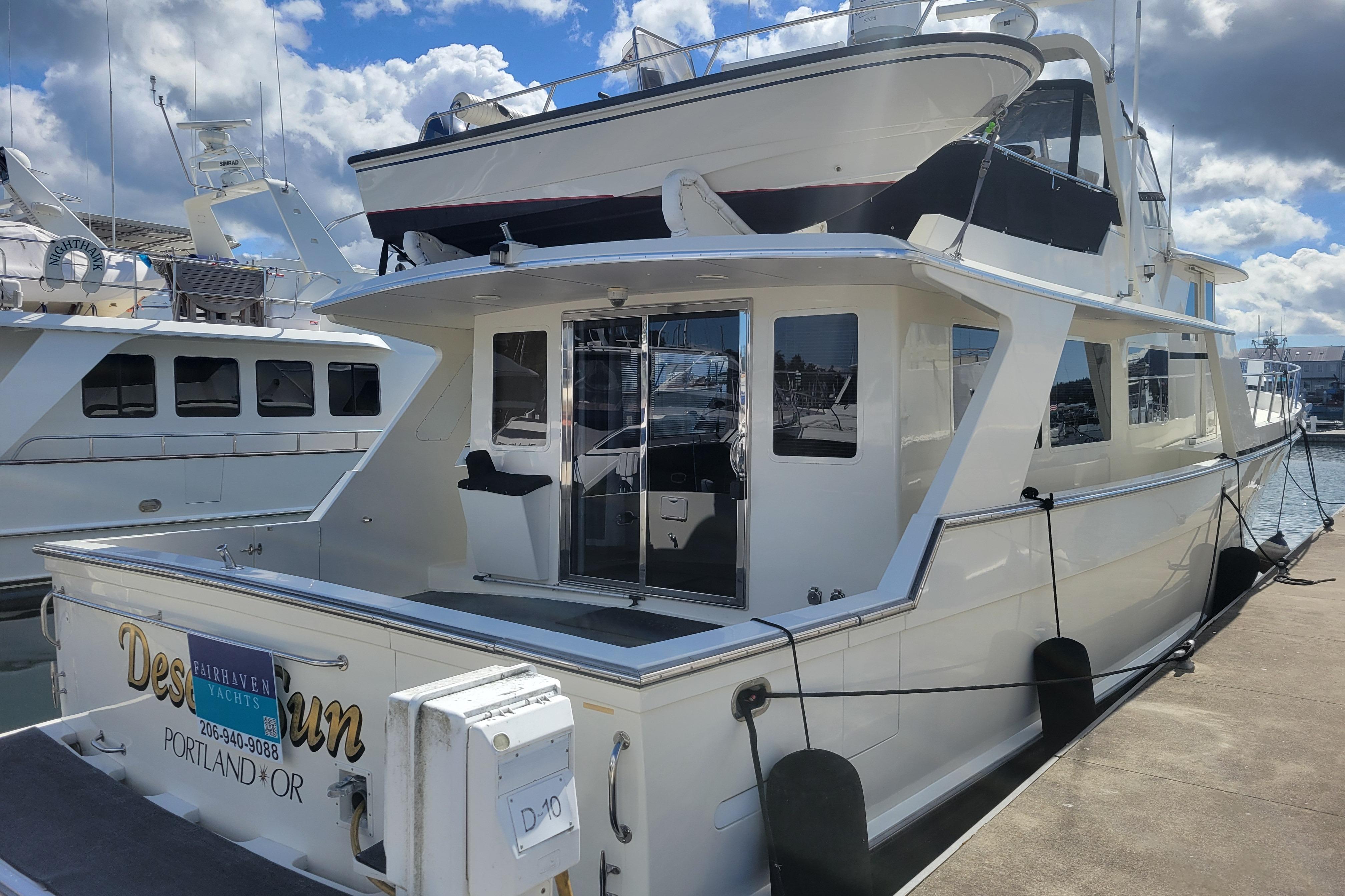 1998 Tollycraft 65 Pilothouse yacht docked in a marina under a partly cloudy sky.