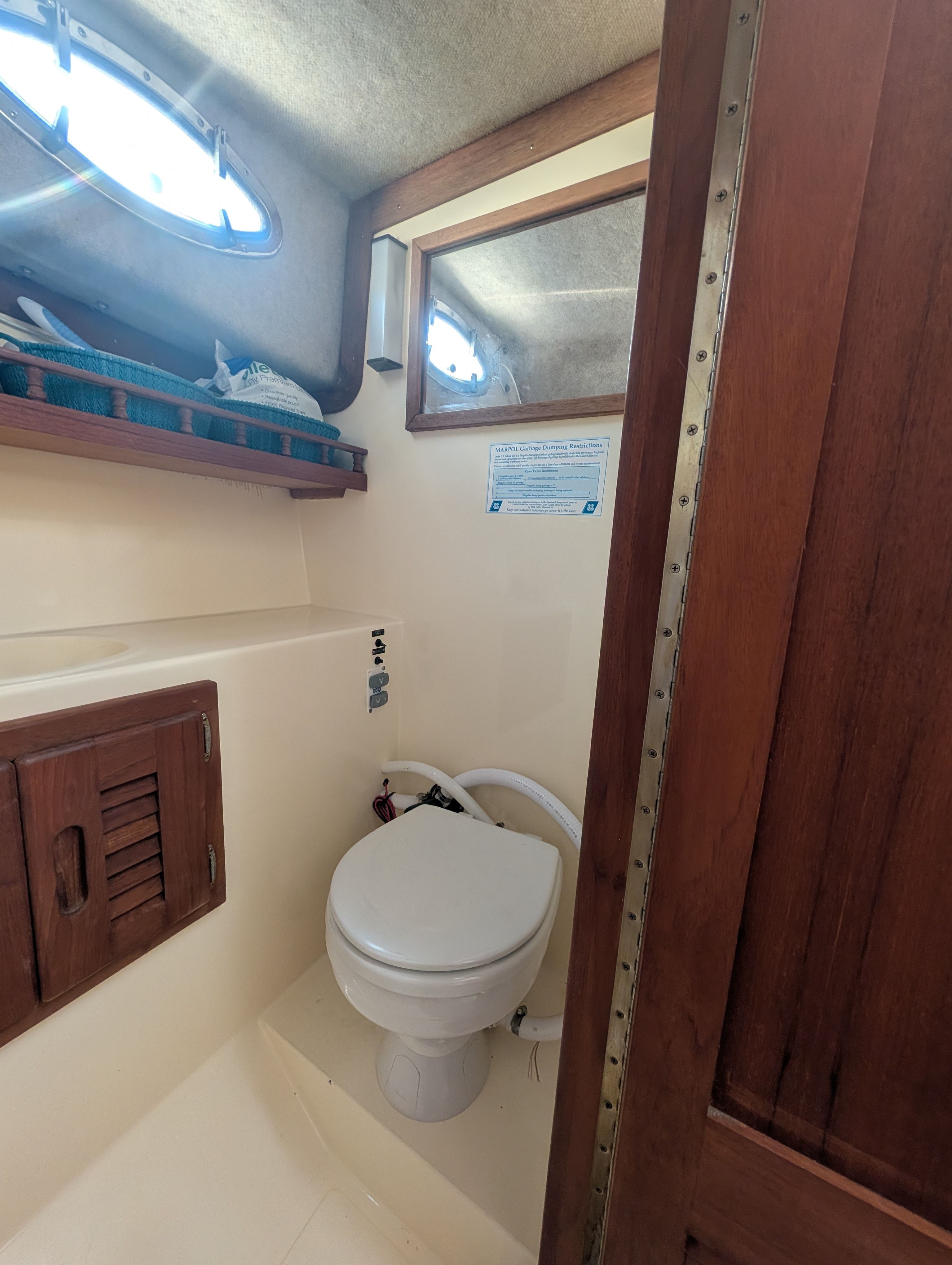 The image shows a boat toilet with wooden doors and a small window.