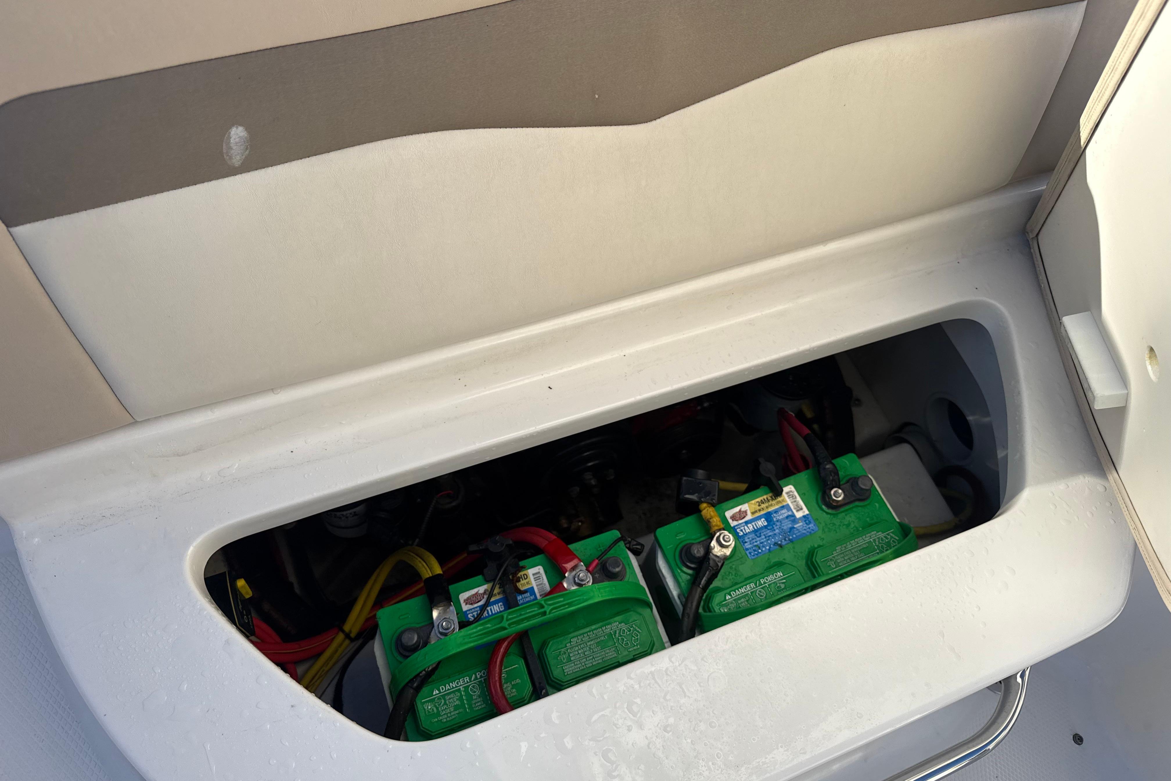 2012 Chaparral 246 SSi boat battery compartment with visible green batteries.