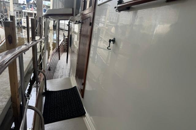 1986 Kadey-Krogen 42 yacht deck with wooden door and railing, docked at marina.
