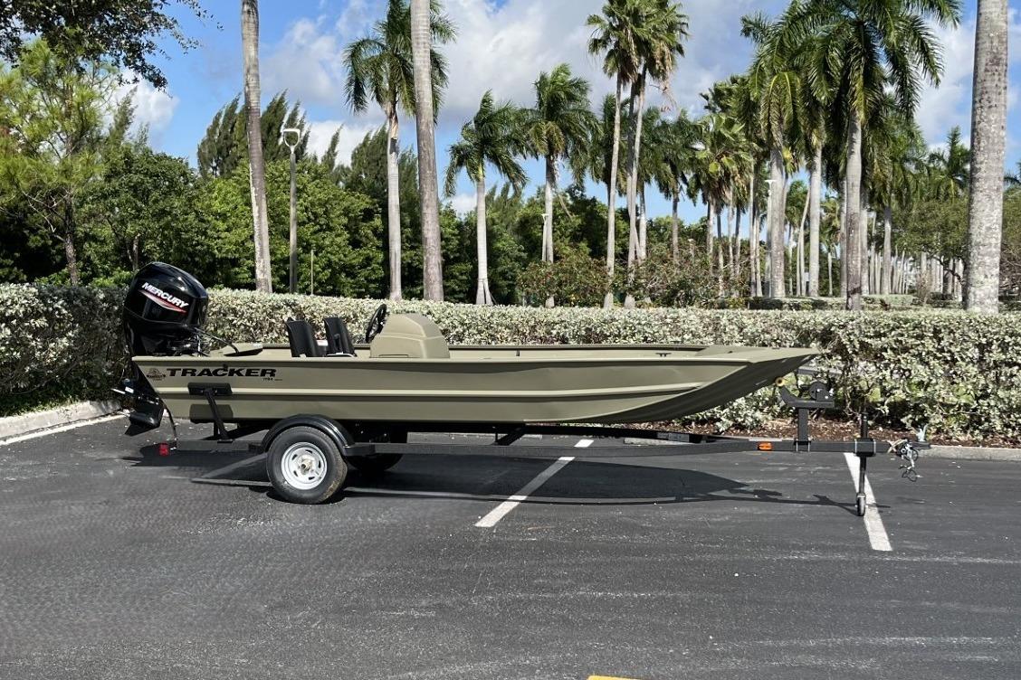 2026 Tracker Grizzly 1754 SC boat on trailer, parked outdoors with palm trees in background.