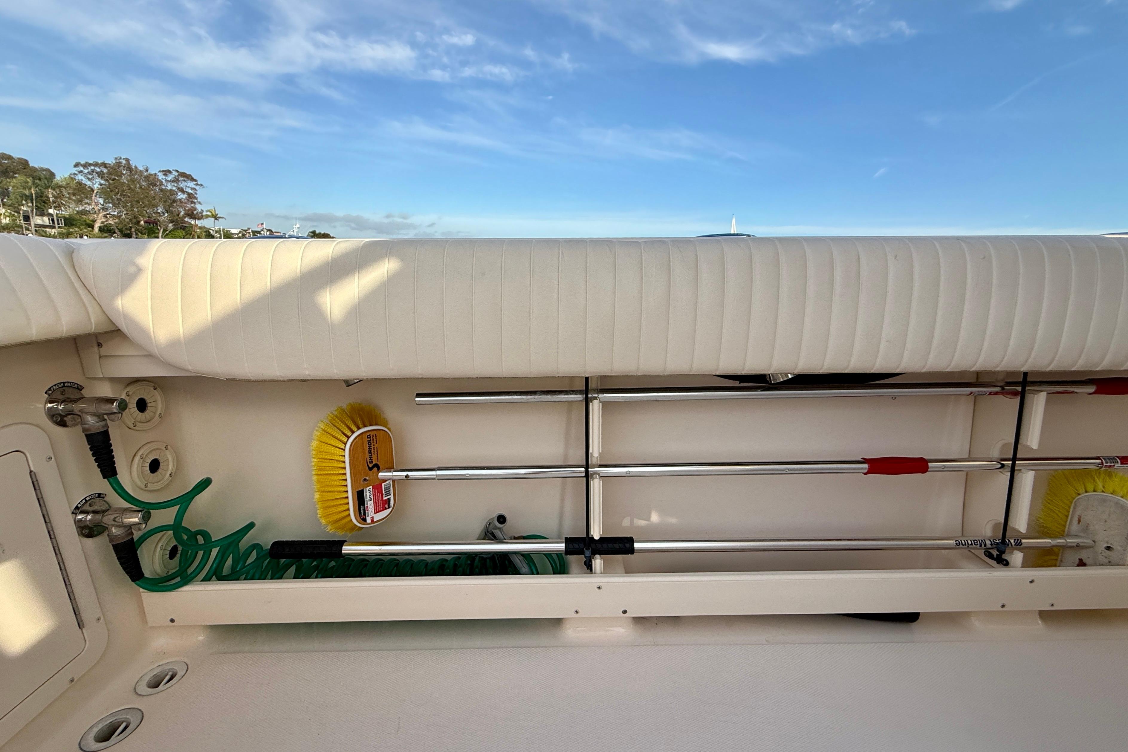 Storage compartment on a 2012 Grady-White Canyon 336 boat, featuring cleaning tools and hose.