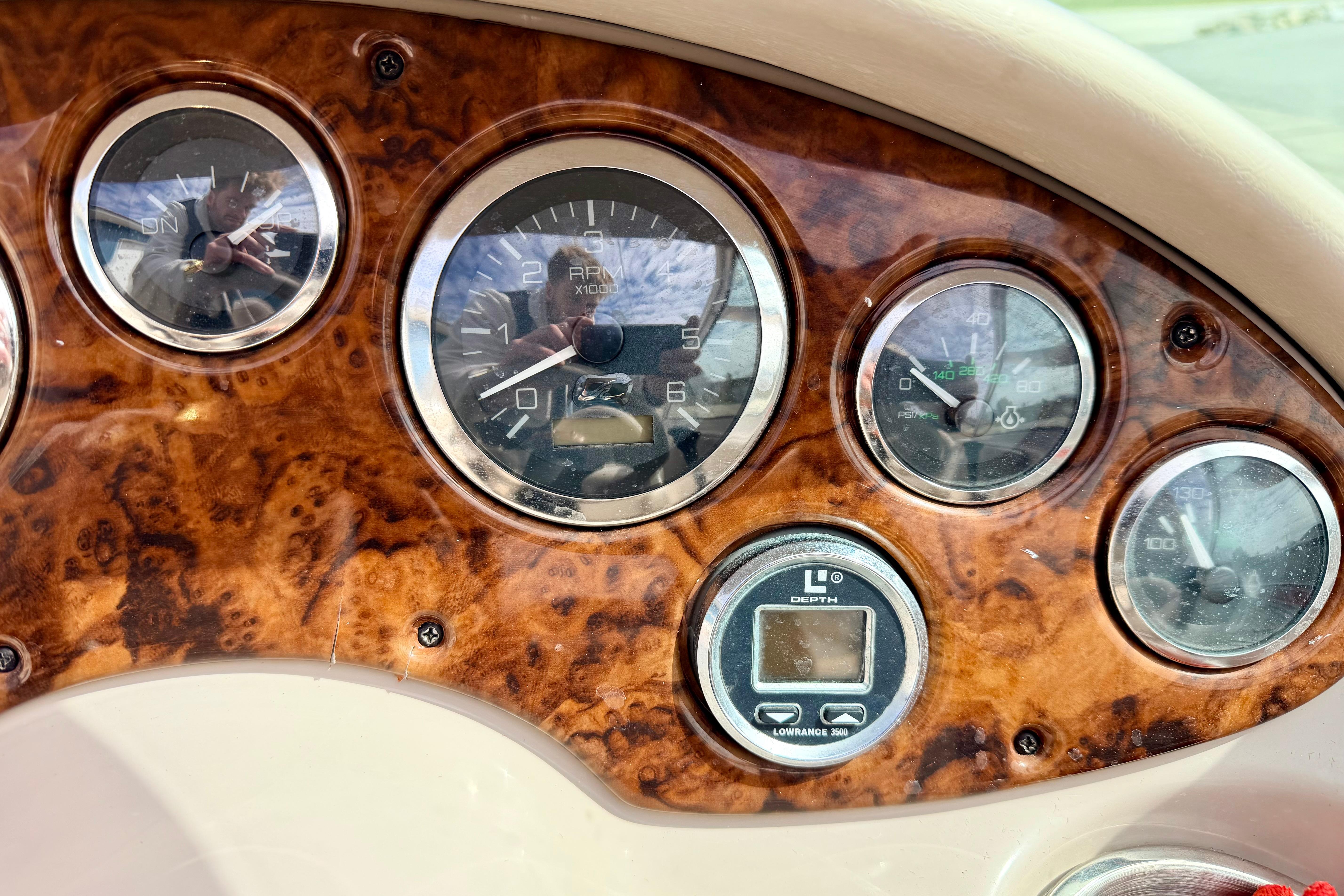 Dashboard of a 2003 Sea Ray 200 Sundeck boat with wood grain finish and gauges.