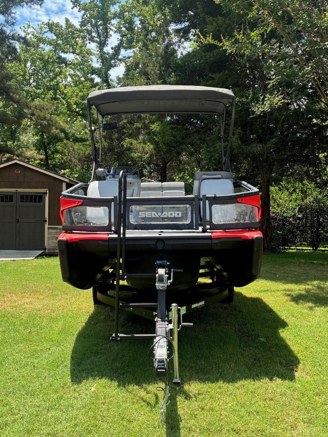 A 2023 Sea-Doo Switch Sport 18 on a trailer on a grassy lawn.