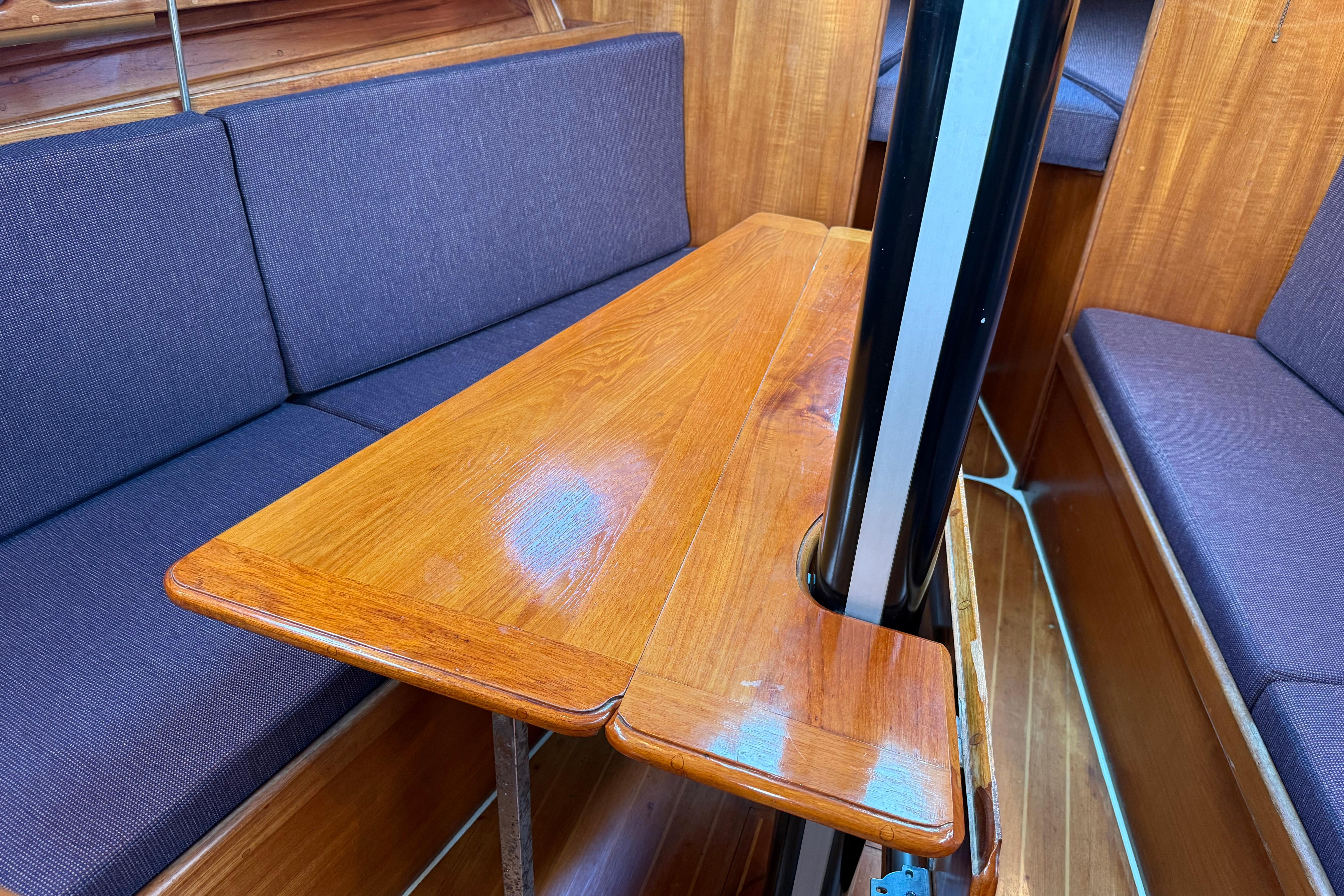 Interior of 1988 Ericson 32-200 sailboat with wooden table and blue cushioned seating.