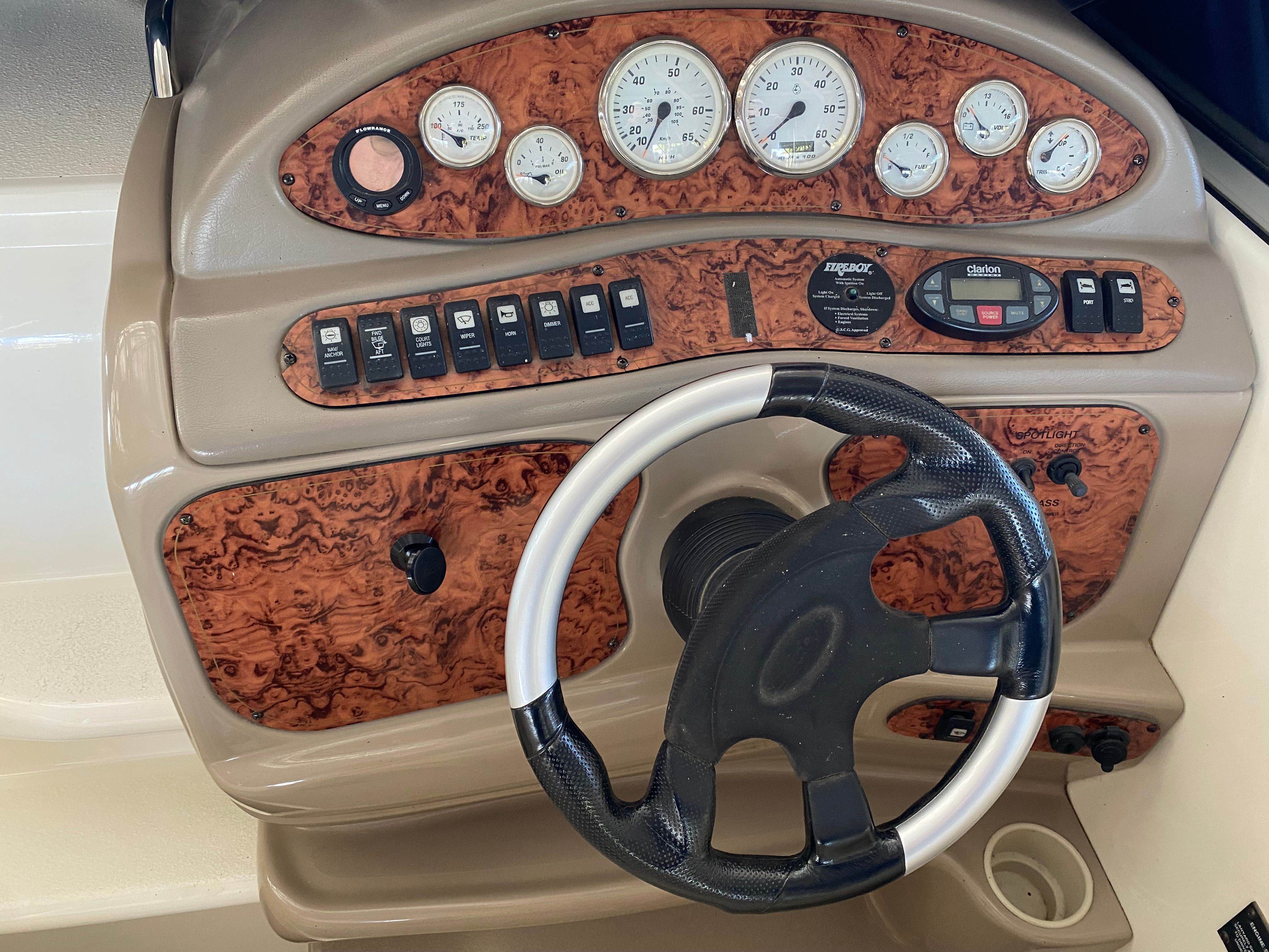 The image shows a boat dashboard with wood paneling and multiple gauges.