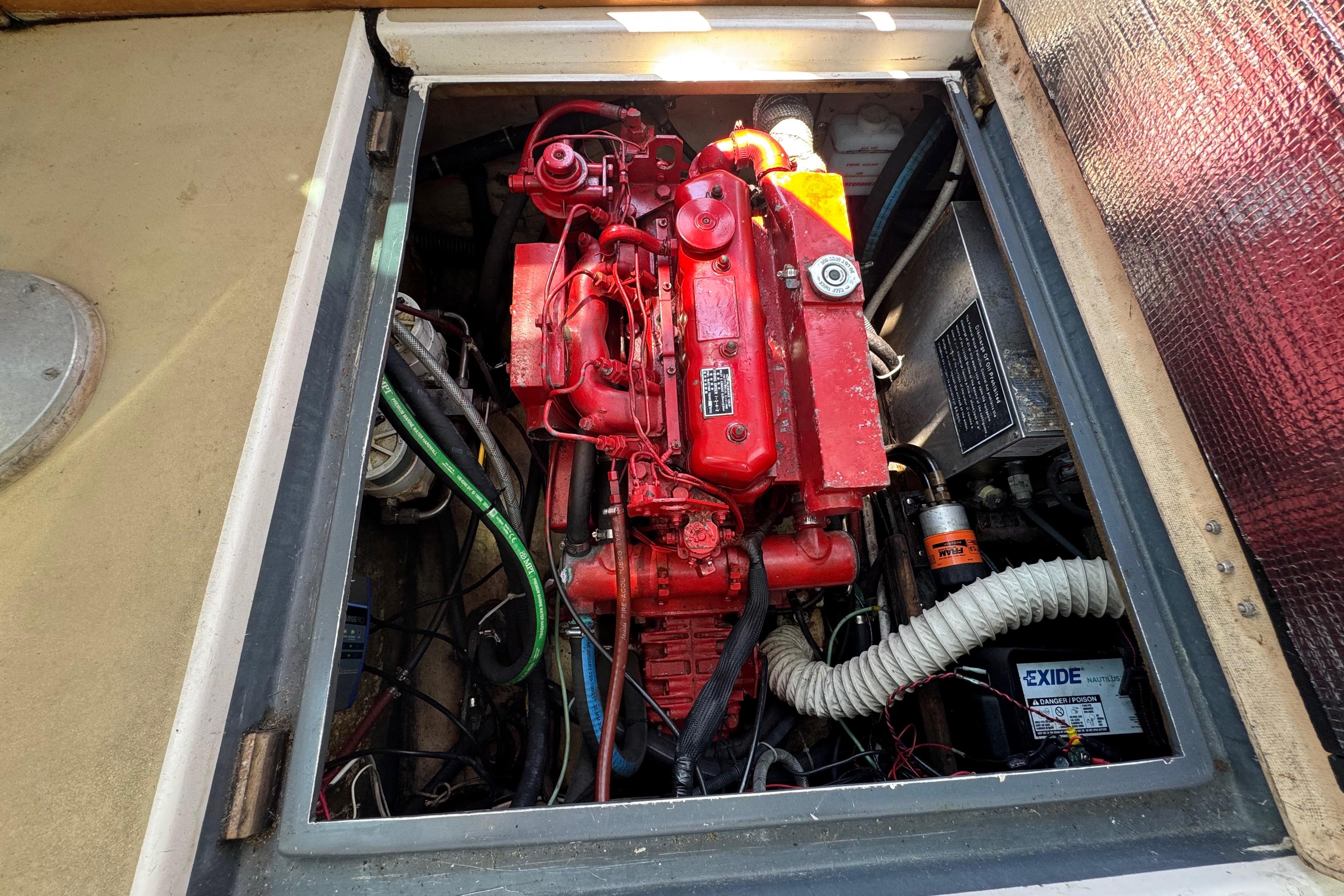Engine compartment of a 1989 Cape Dory 30 Motorsailer, featuring a red engine and wiring.
