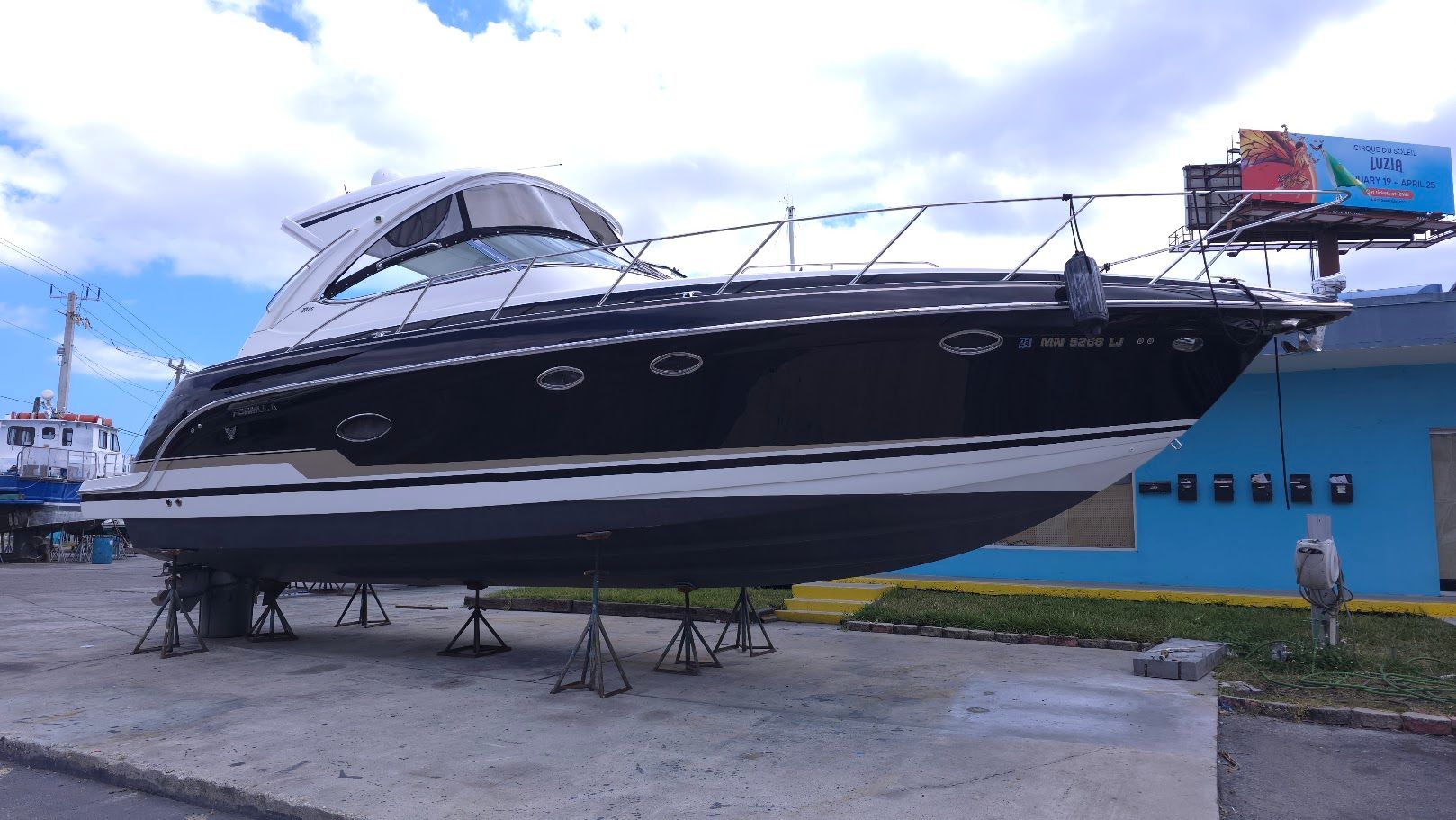 A black motor yacht on stands, with a white superstructure and blue sky in the background.