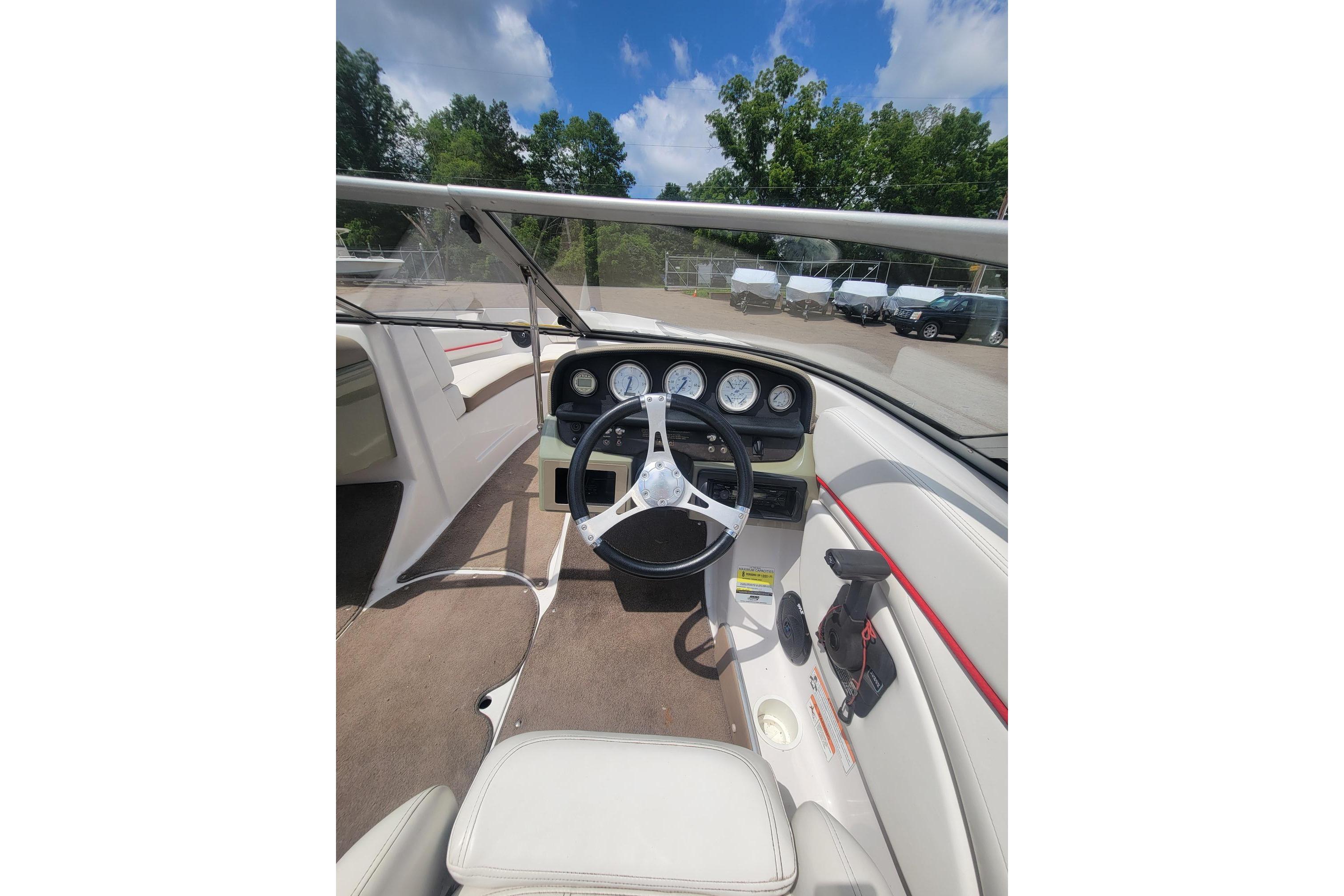 2007 Four Winns 200 Horizon boat dashboard with steering wheel and gauges under blue sky.