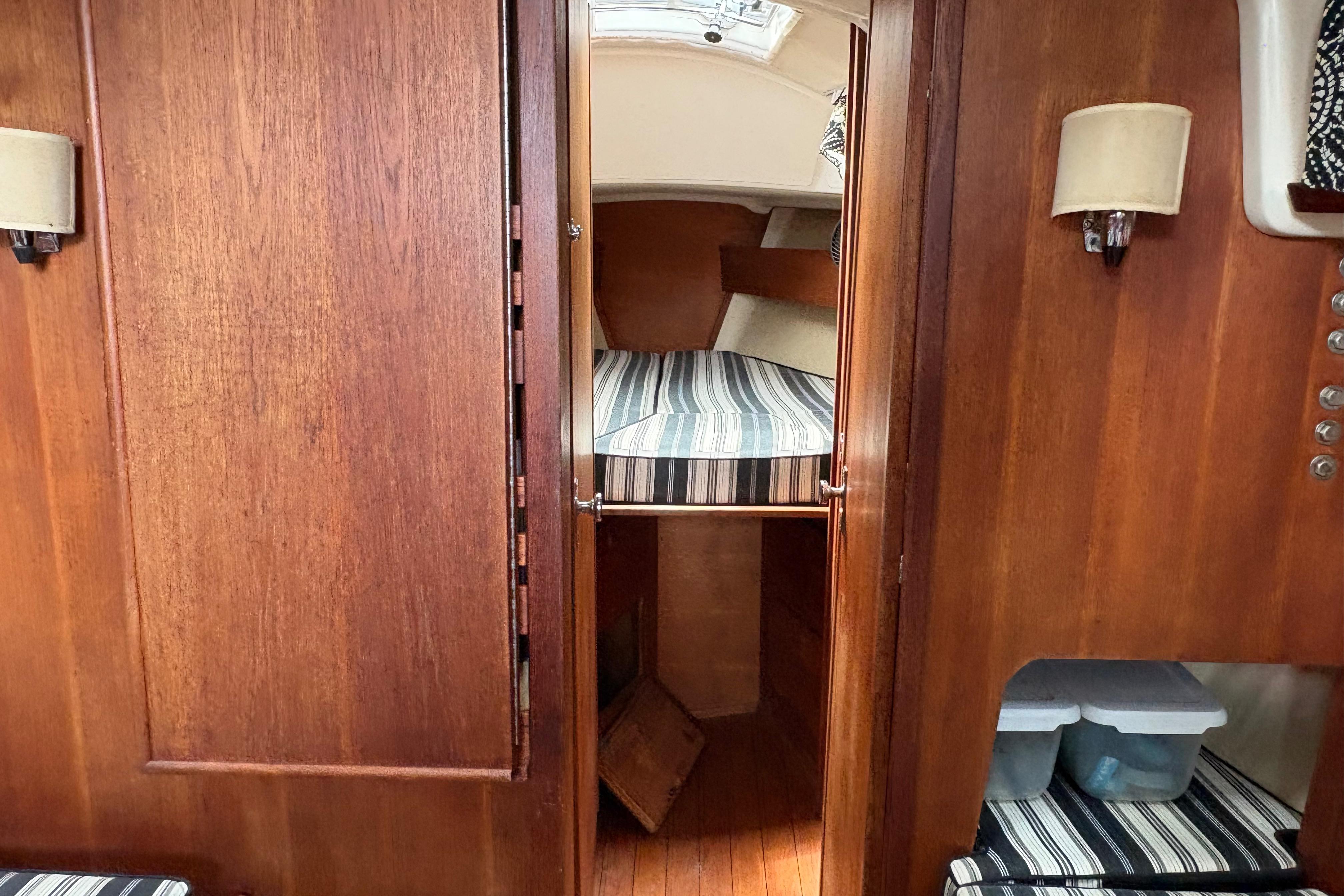 Interior of 1981 Sabre 31 sailboat with wooden finish and striped bedding.
