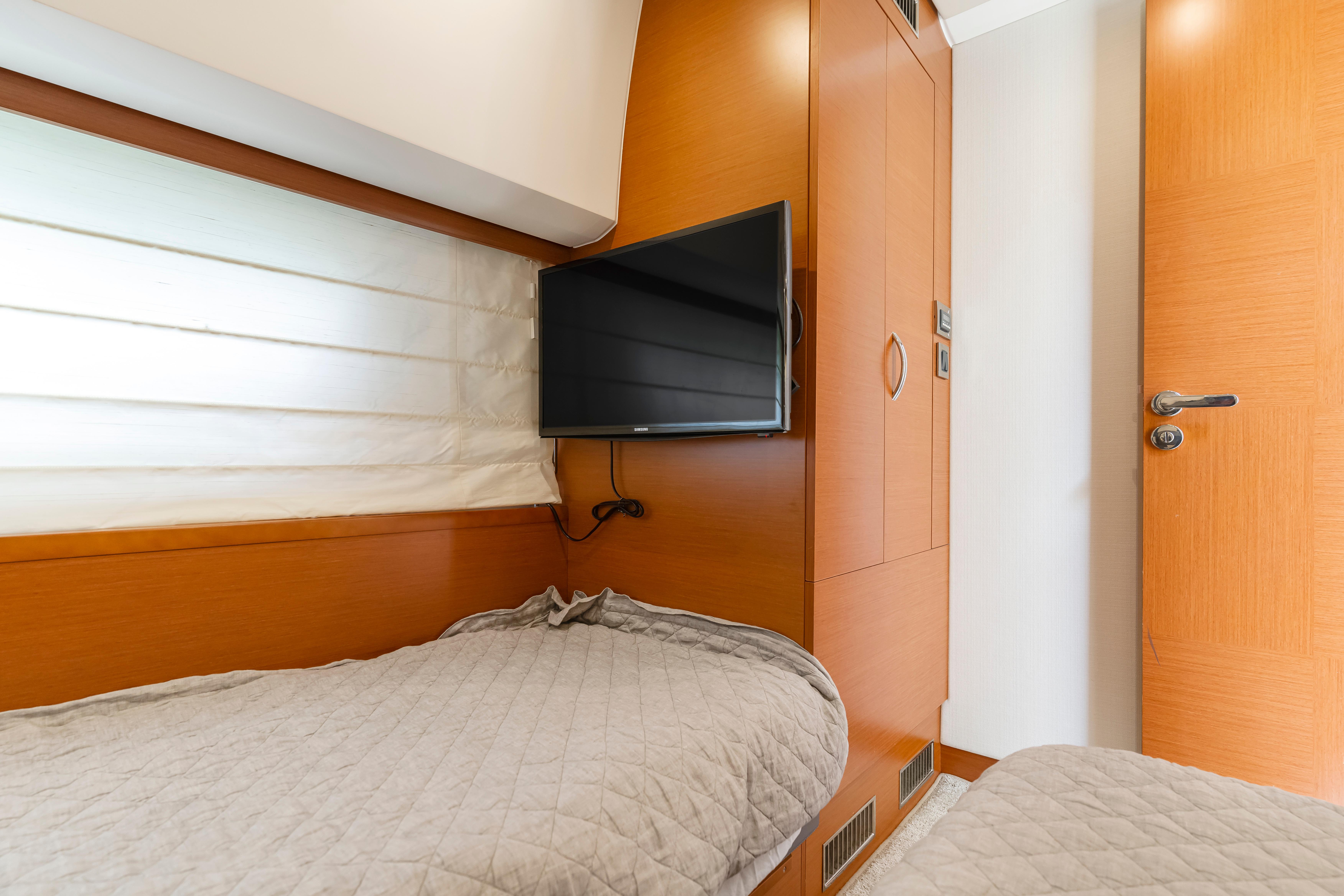 Cozy cabin interior of 2017 Prestige 500 yacht with twin beds and wall-mounted TV.