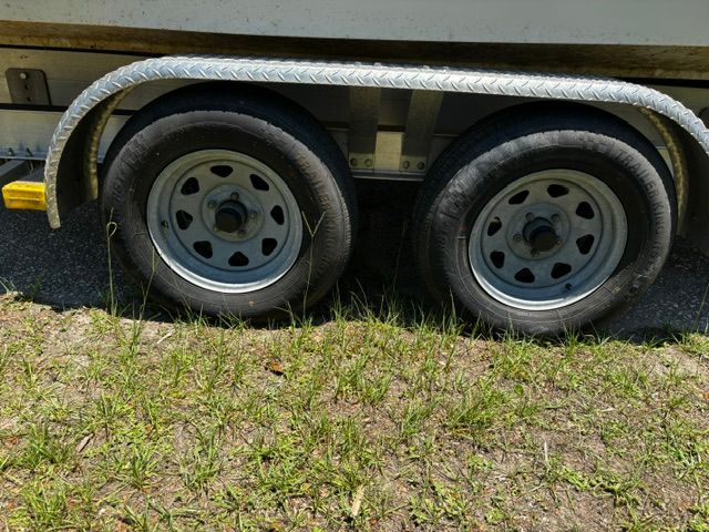 Close-up of a boat trailer with two tires on grass.