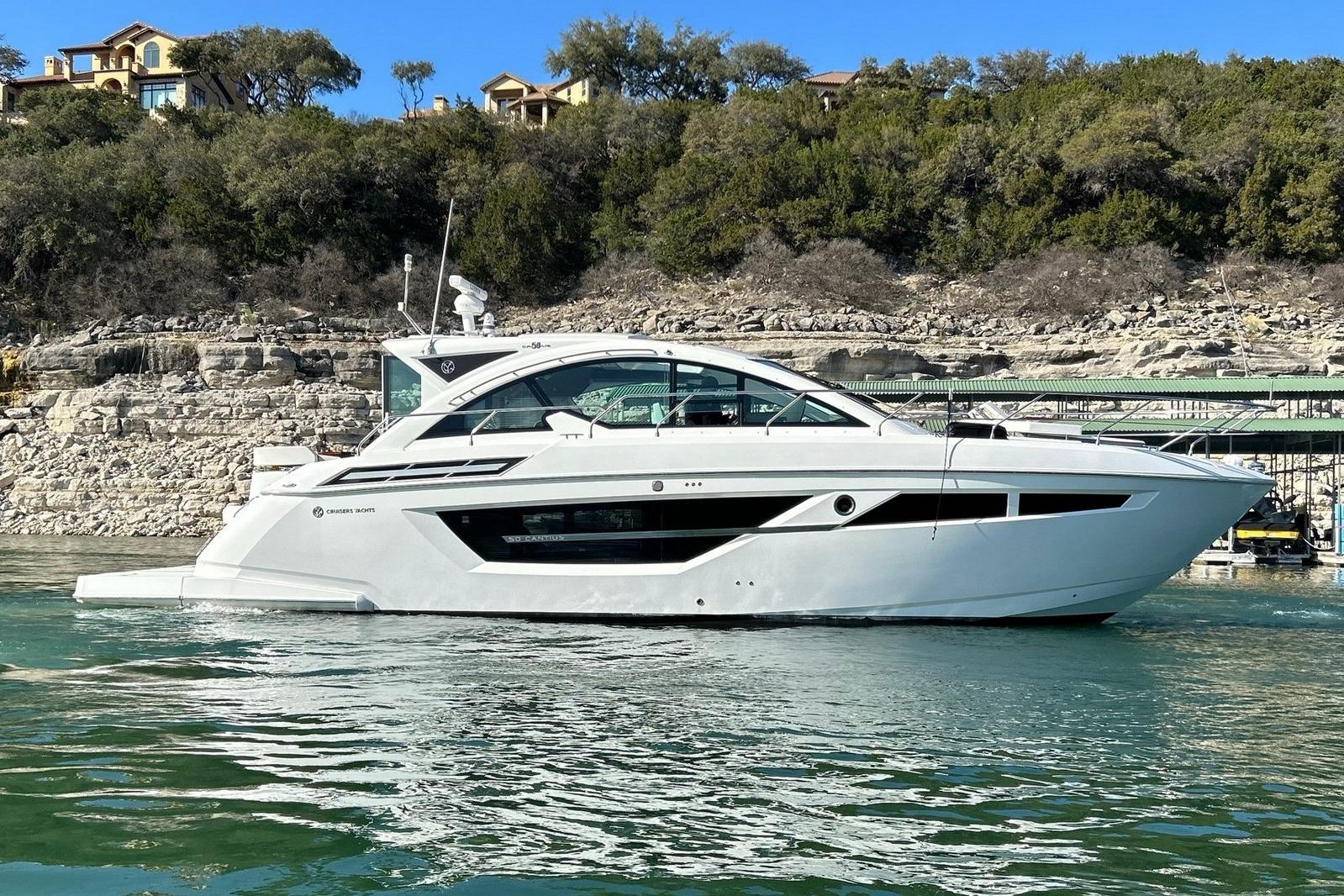 2021 Cruisers Yachts 50 Cantius on serene water, with lush greenery in the background.