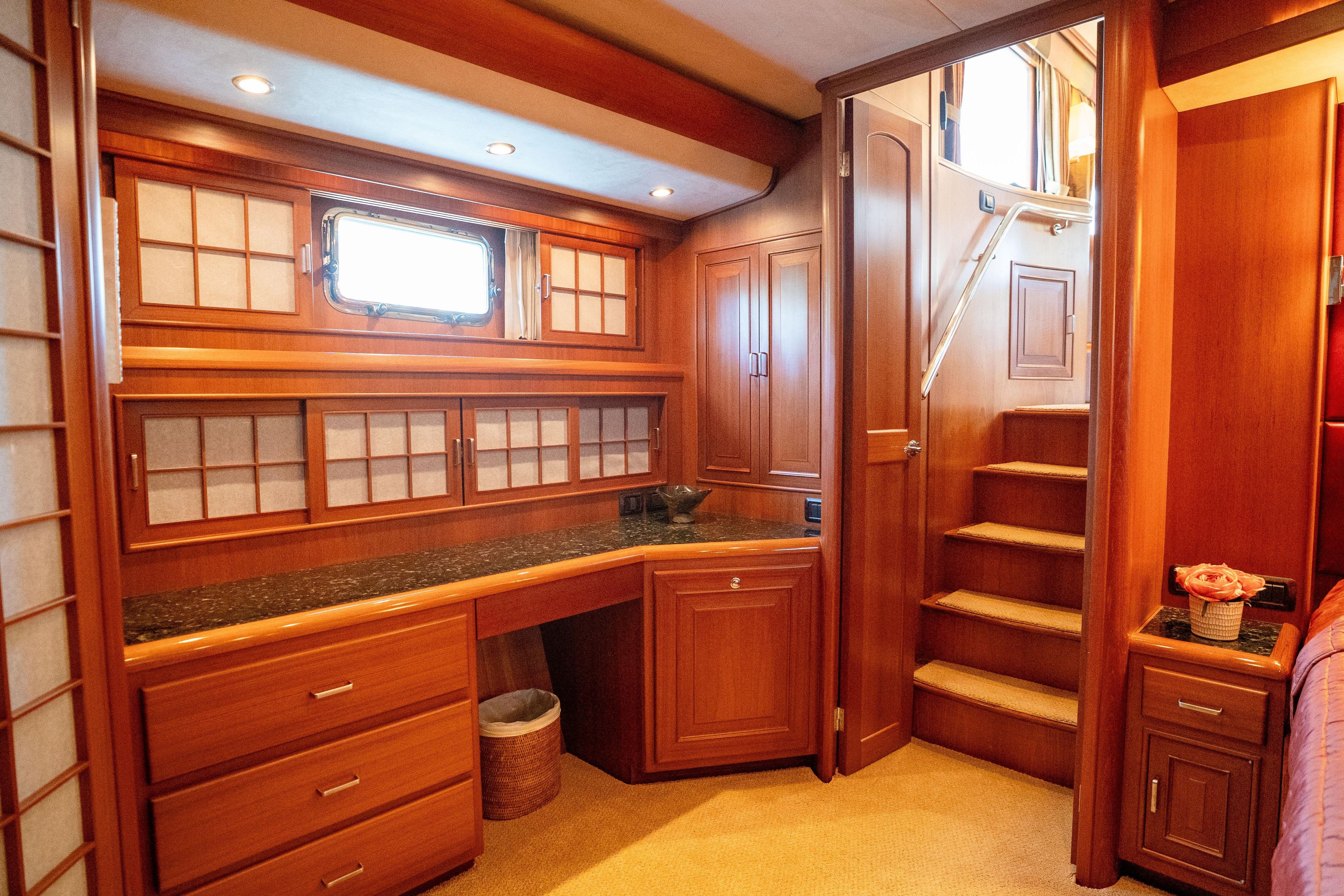 Luxurious wooden interior of a 2006 Fleming 75 yacht with elegant cabinetry and stairs.