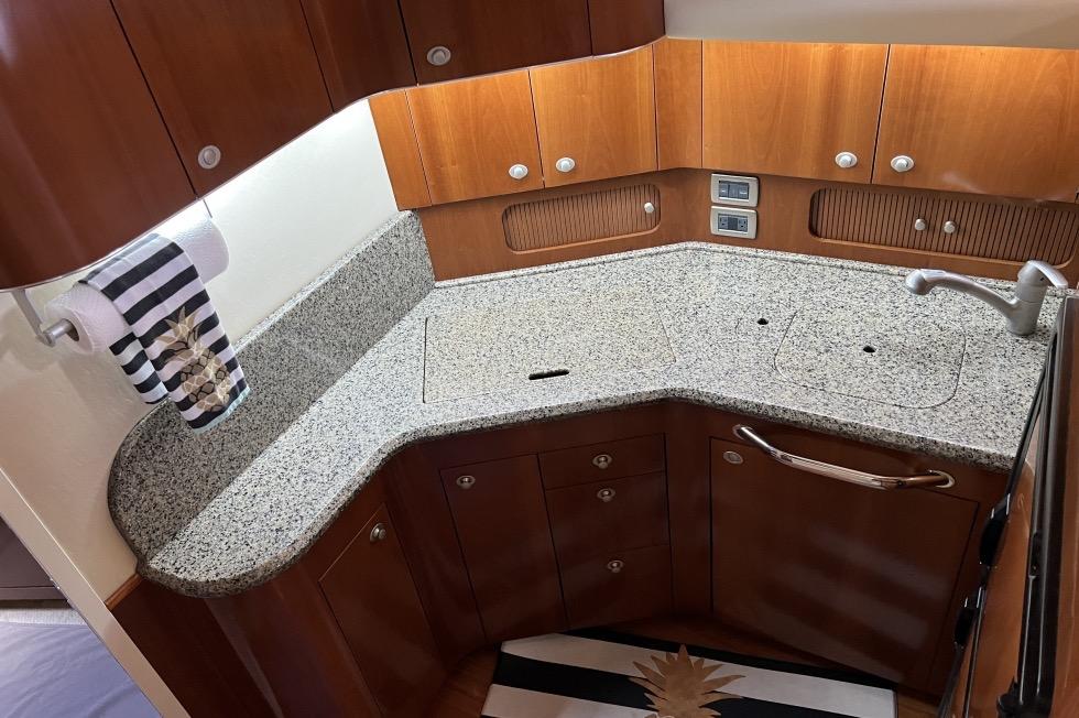 Luxurious kitchen area in 2005 Sea Ray 390 Motor Yacht with granite countertops and wooden cabinetry.