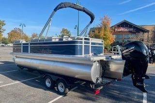 2026 Sun Tracker SportFish 22 XP3 pontoon boat in parking lot, rear view.