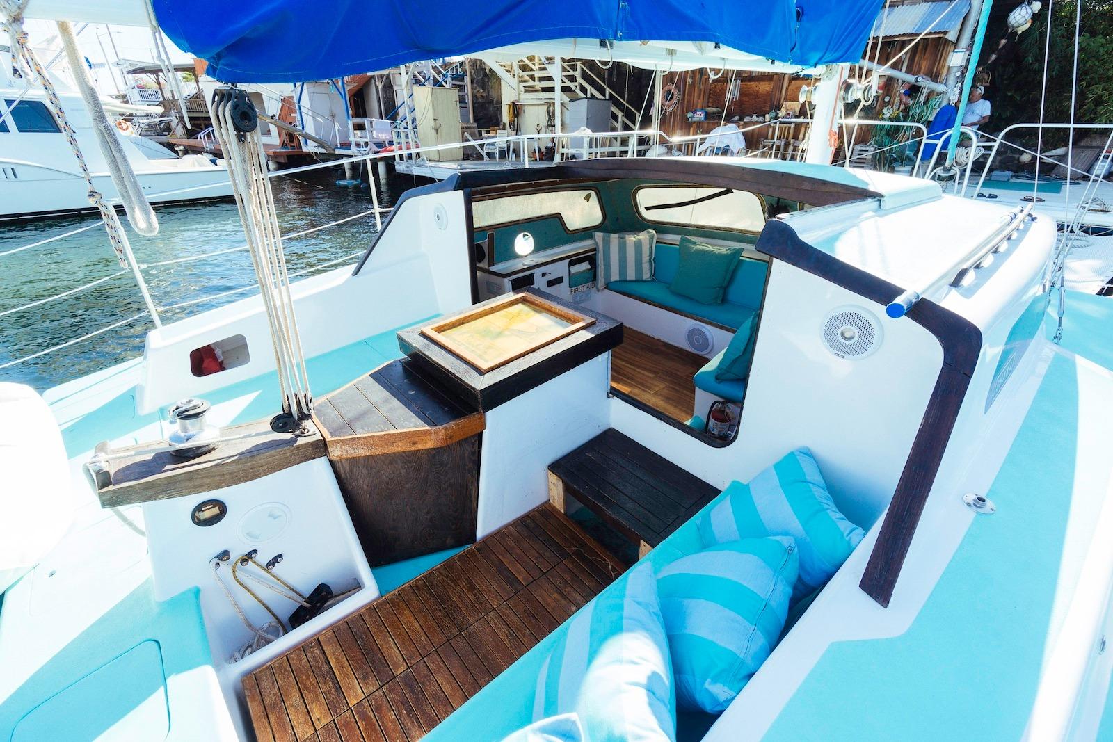 1978 CSK Beach Cat sailboat interior with blue cushions and wooden accents, docked at marina.