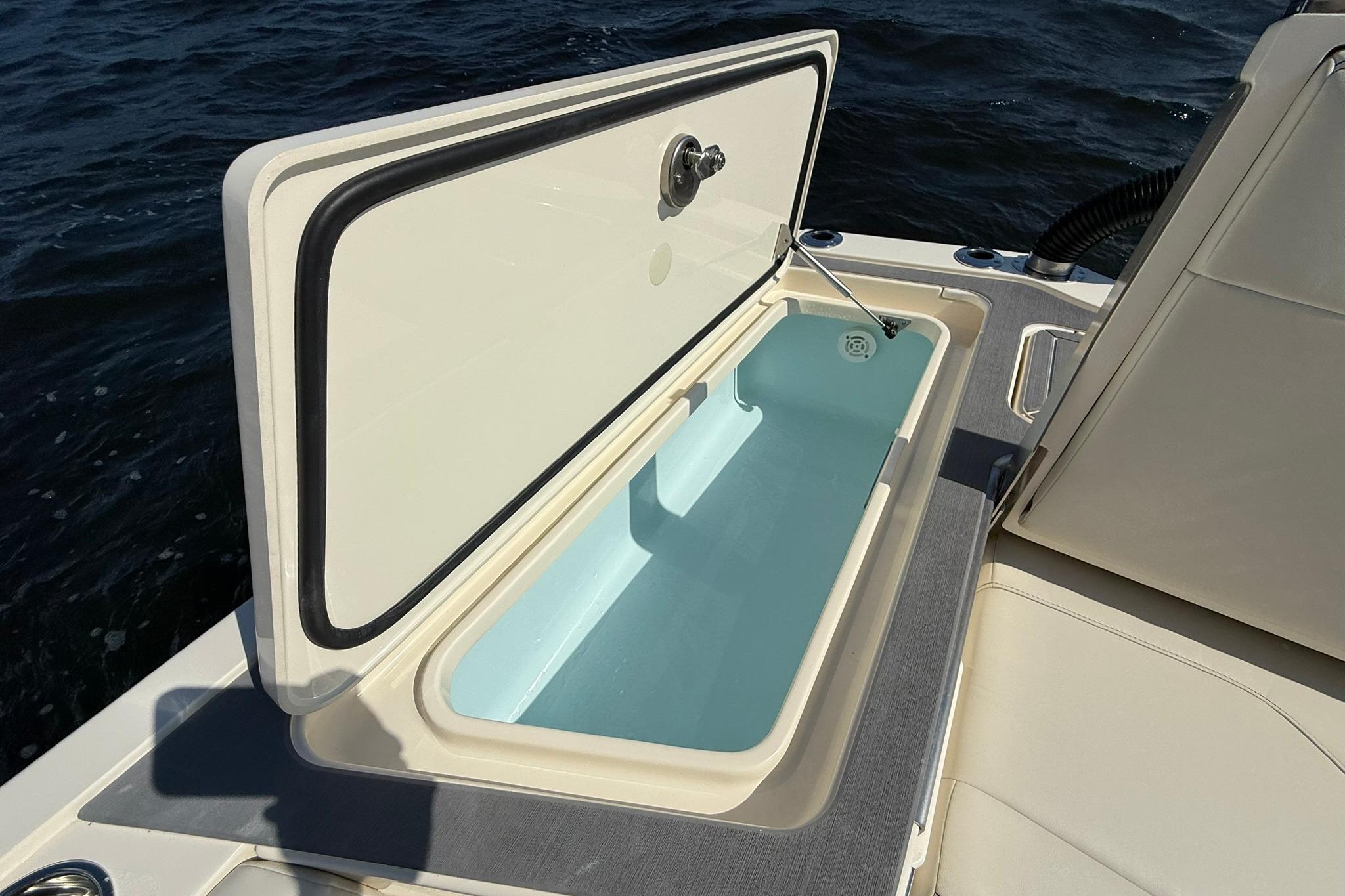 Open storage compartment on 2026 Scout 281 XSS boat, with ocean background.