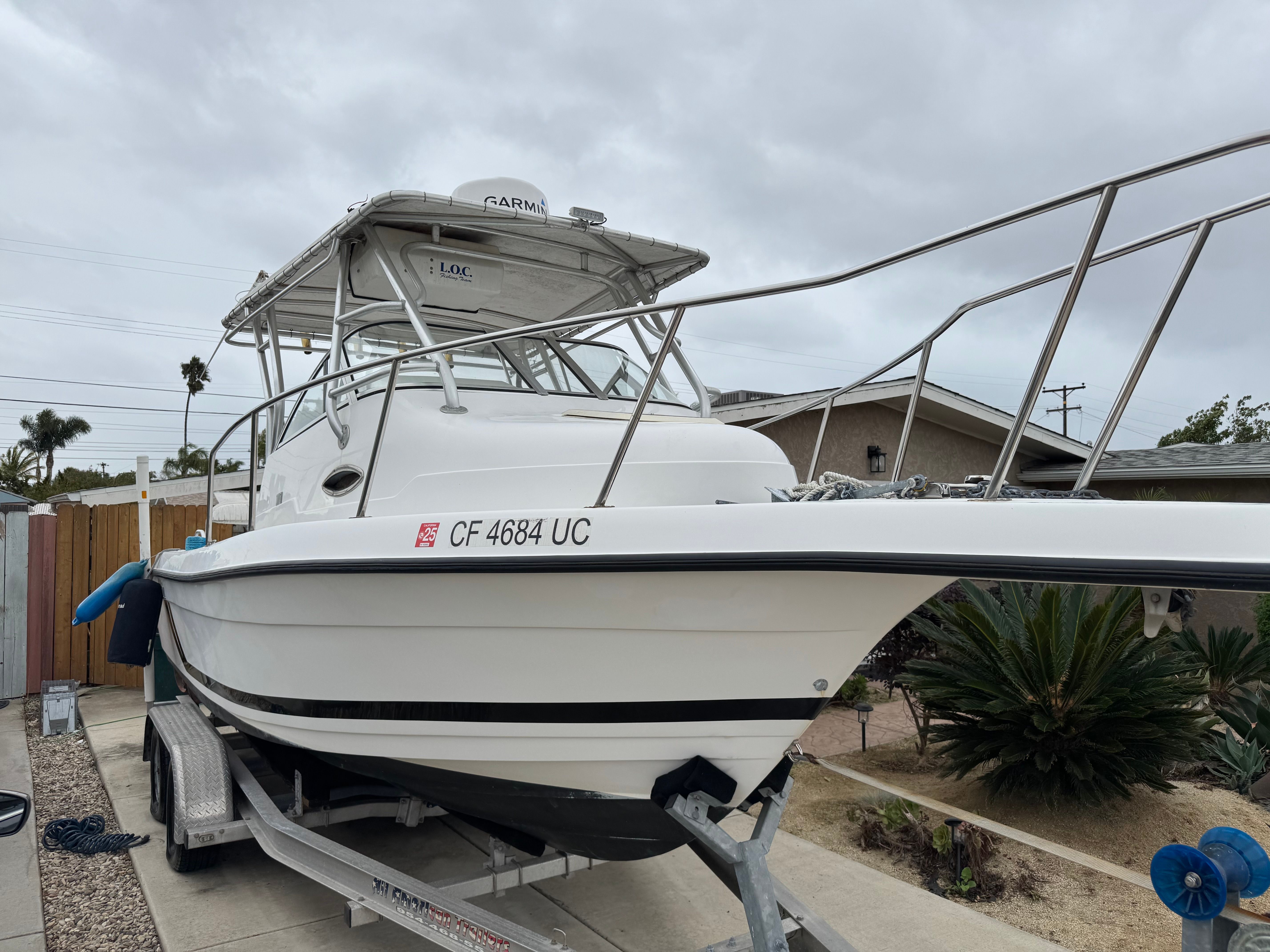 A 1999 Cobia Walkaround boat is on a trailer in a yard.