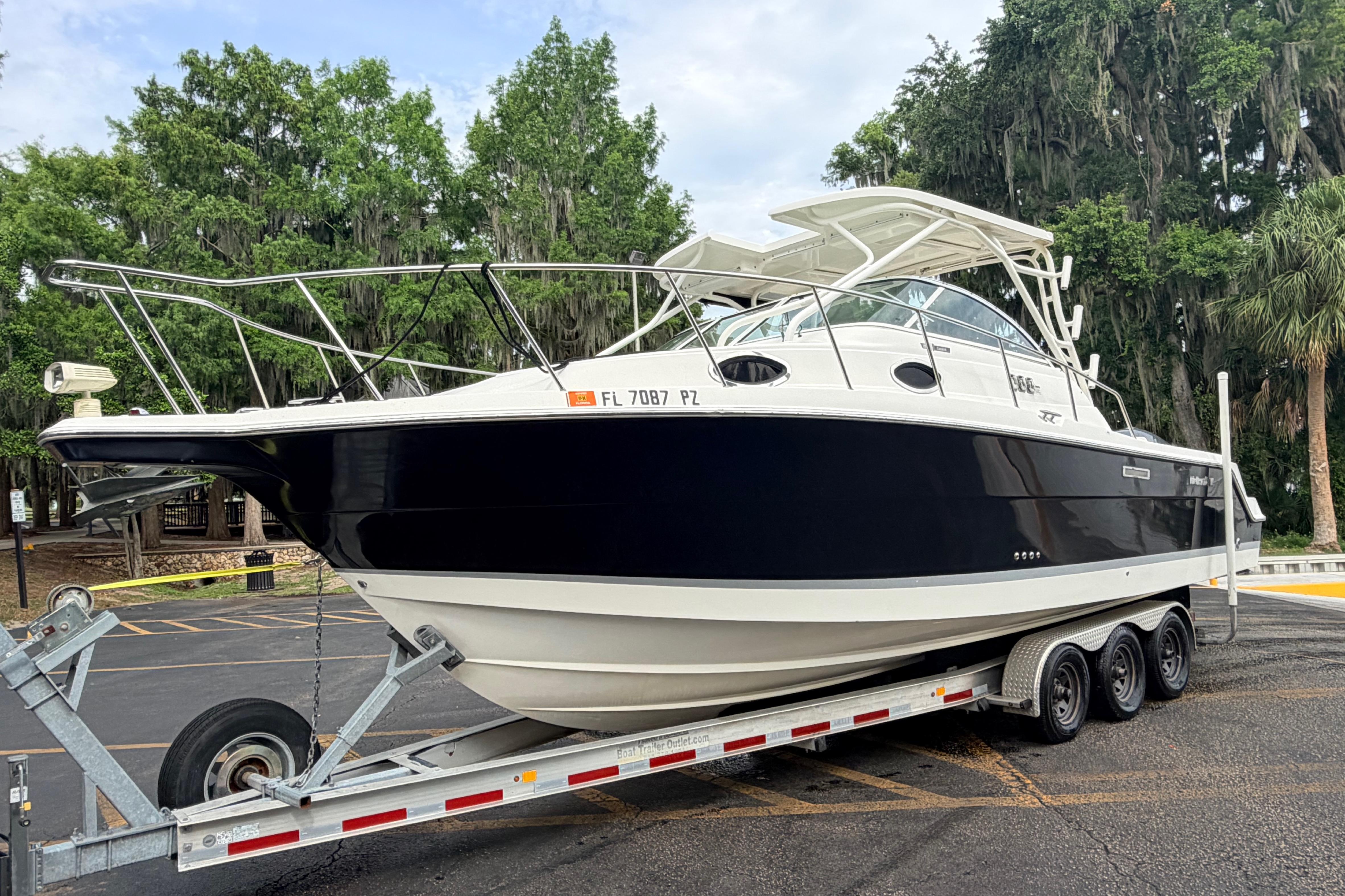 2015 Wellcraft 290 Coastal boat on trailer, parked in a wooded area.