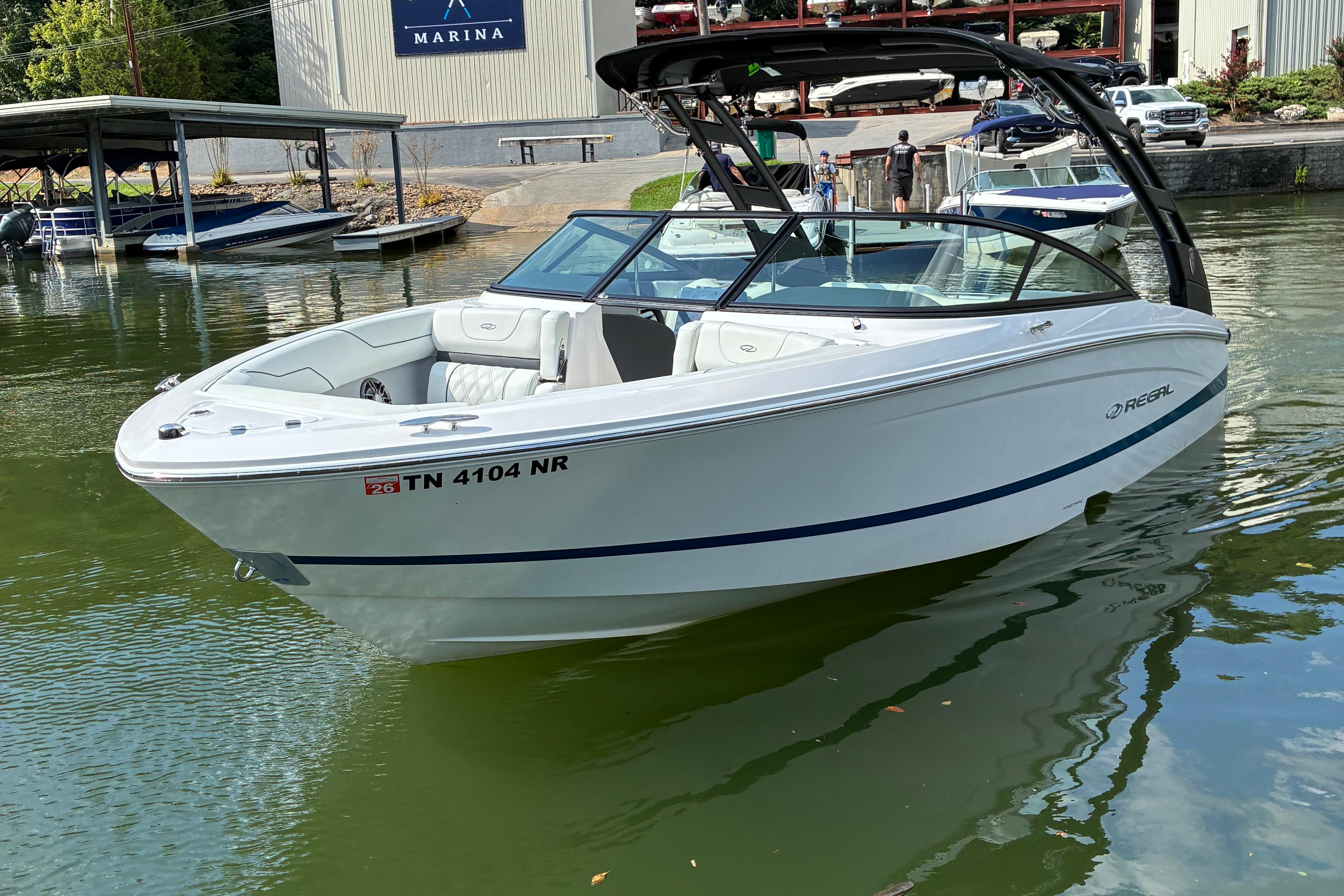 2025 Regal LS2 boat docked at marina, sleek white design, calm water setting.
