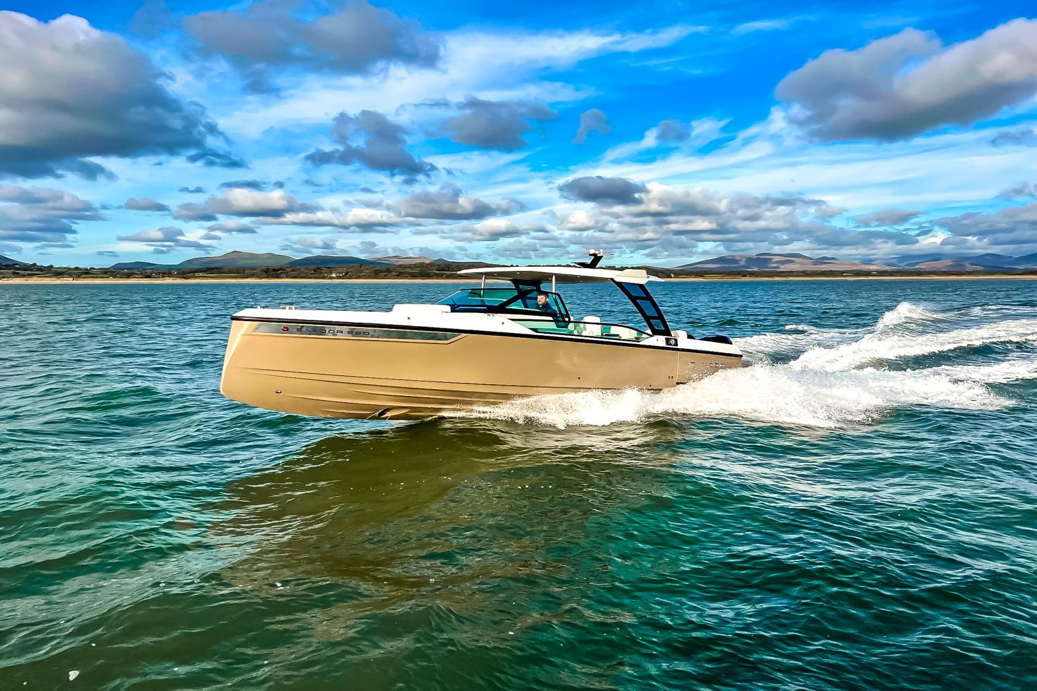 A 2027 Saxdor SX320 GTO speeds across the water under a blue sky.