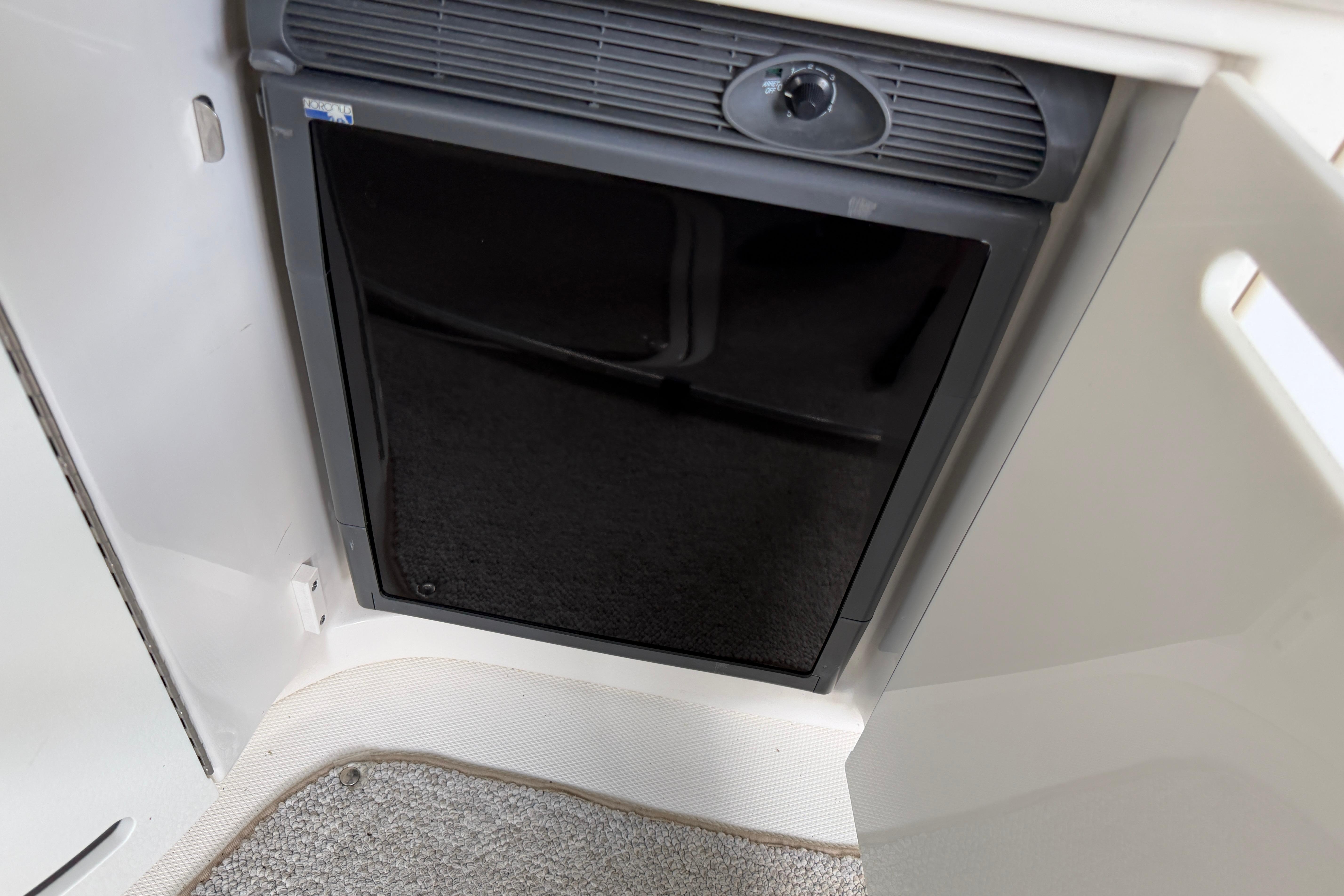 2003 Sea Ray 290 Bowrider interior fridge with black door and control knob.