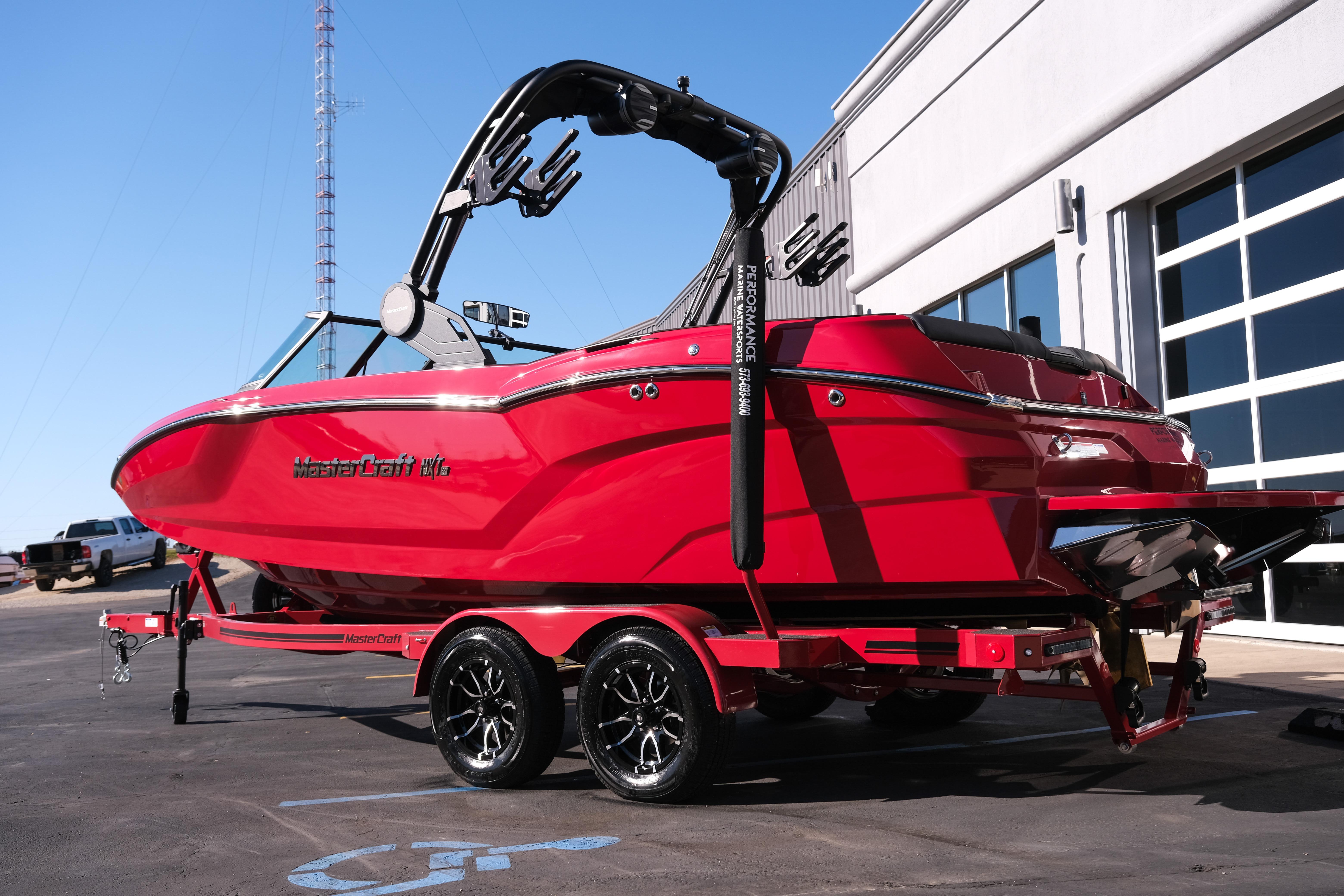 2026 MasterCraft NXT22 boat in vibrant red on a trailer, parked outdoors.