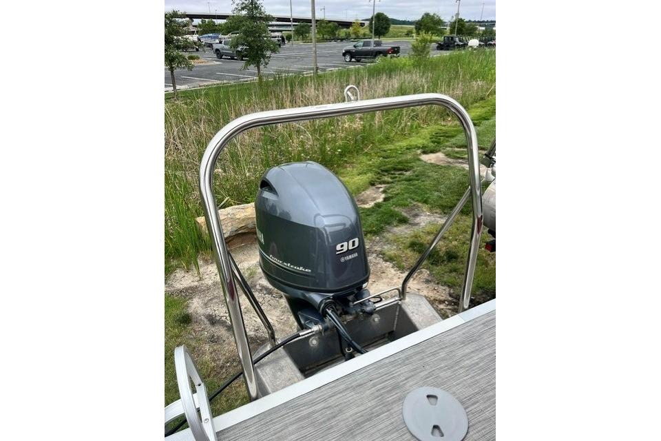 2021 Bennington 205SL boat with Yamaha 90 outboard motor, parked near grassy area.