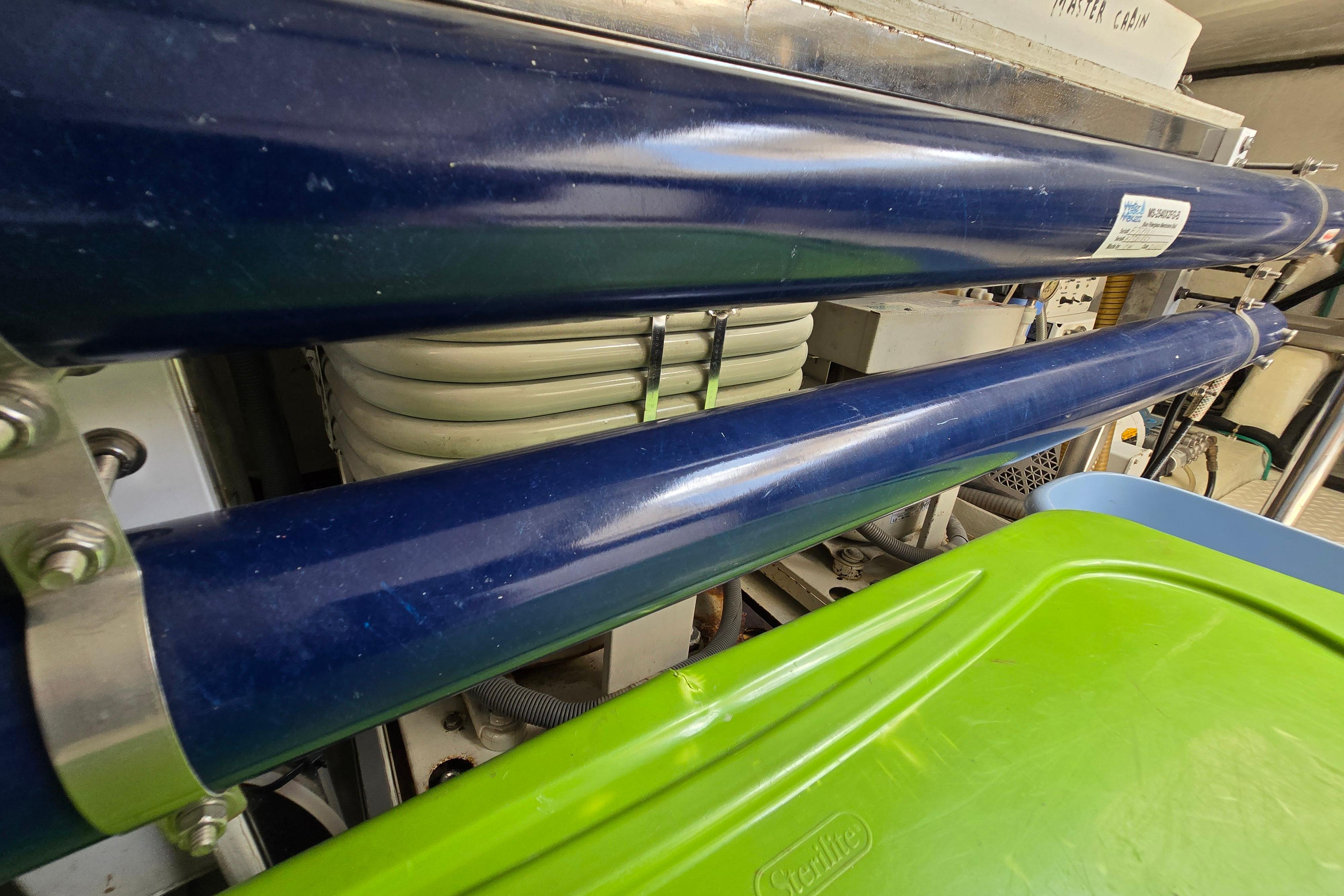 Engine room of a 2004 Grand Harbour 58 yacht, featuring blue pipes and equipment.