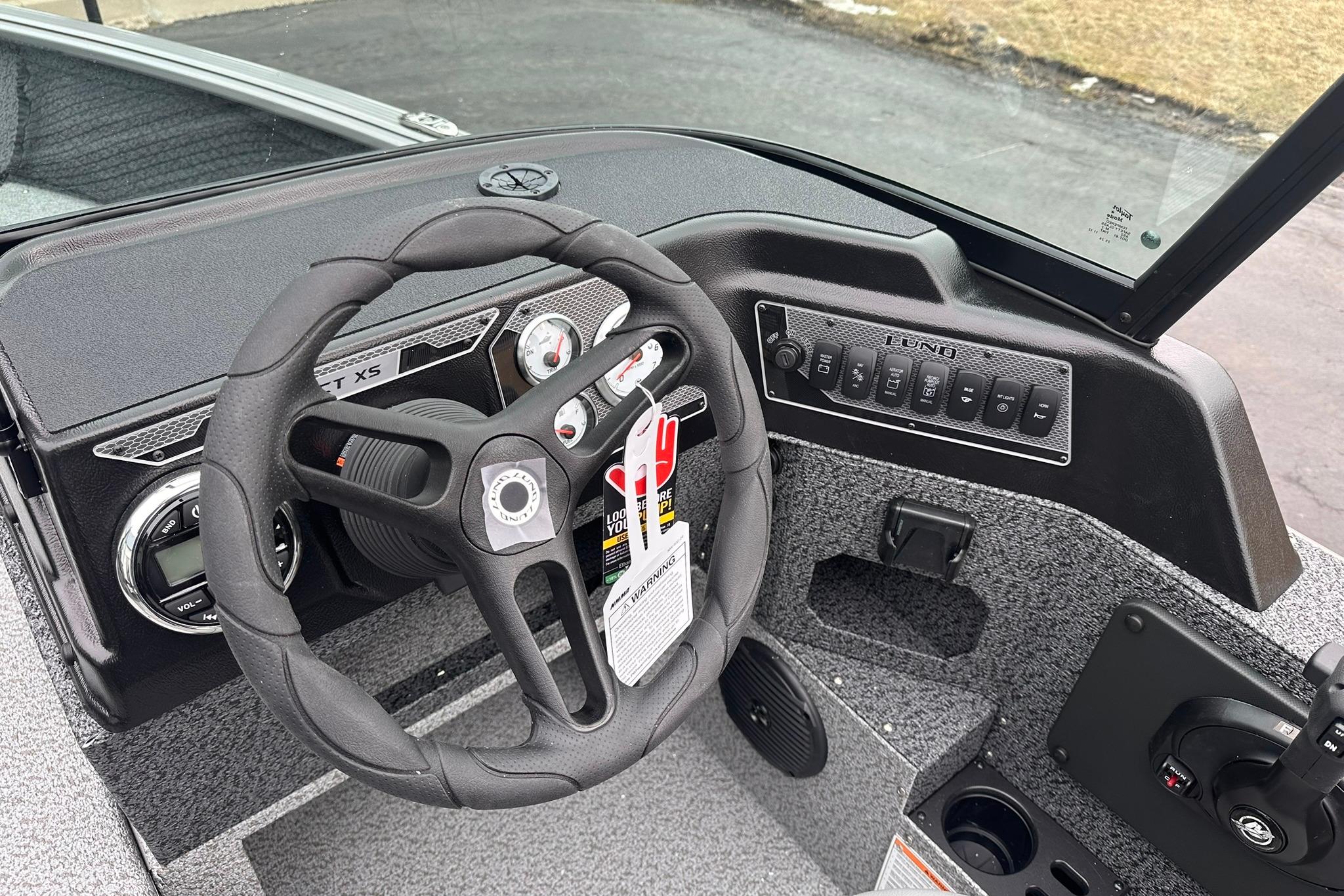2026 Lund 1775 Impact XS Sport boat dashboard with steering wheel and control panel.