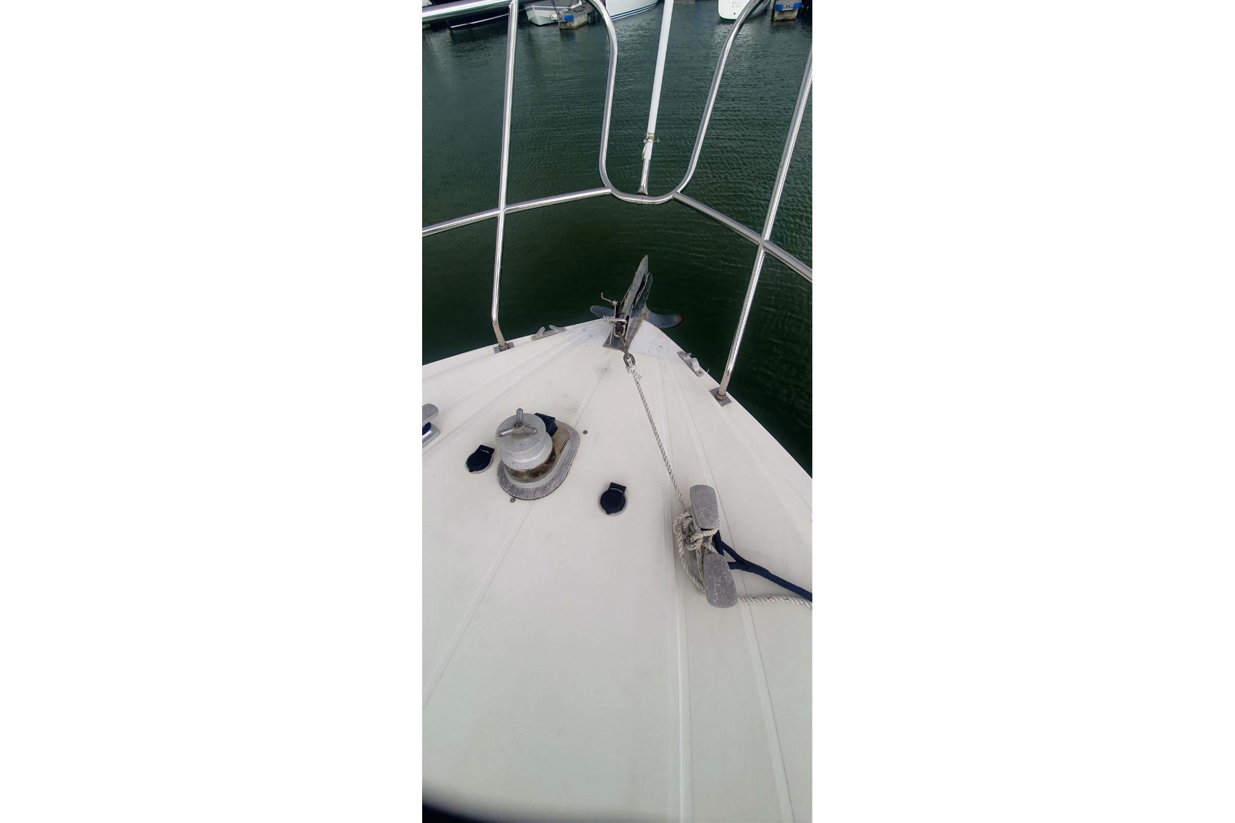 Bow of 1989 Princess 35 yacht with anchor and railing in marina.