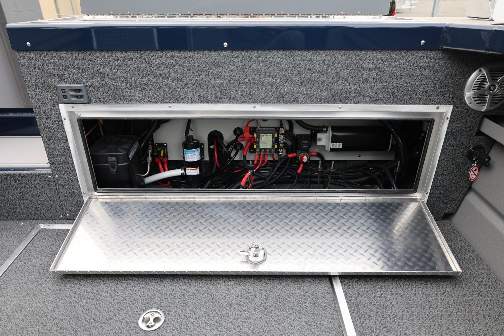 Open storage compartment in 2026 Thunder Jet 24 Alexis Pro boat, showcasing electrical components.
