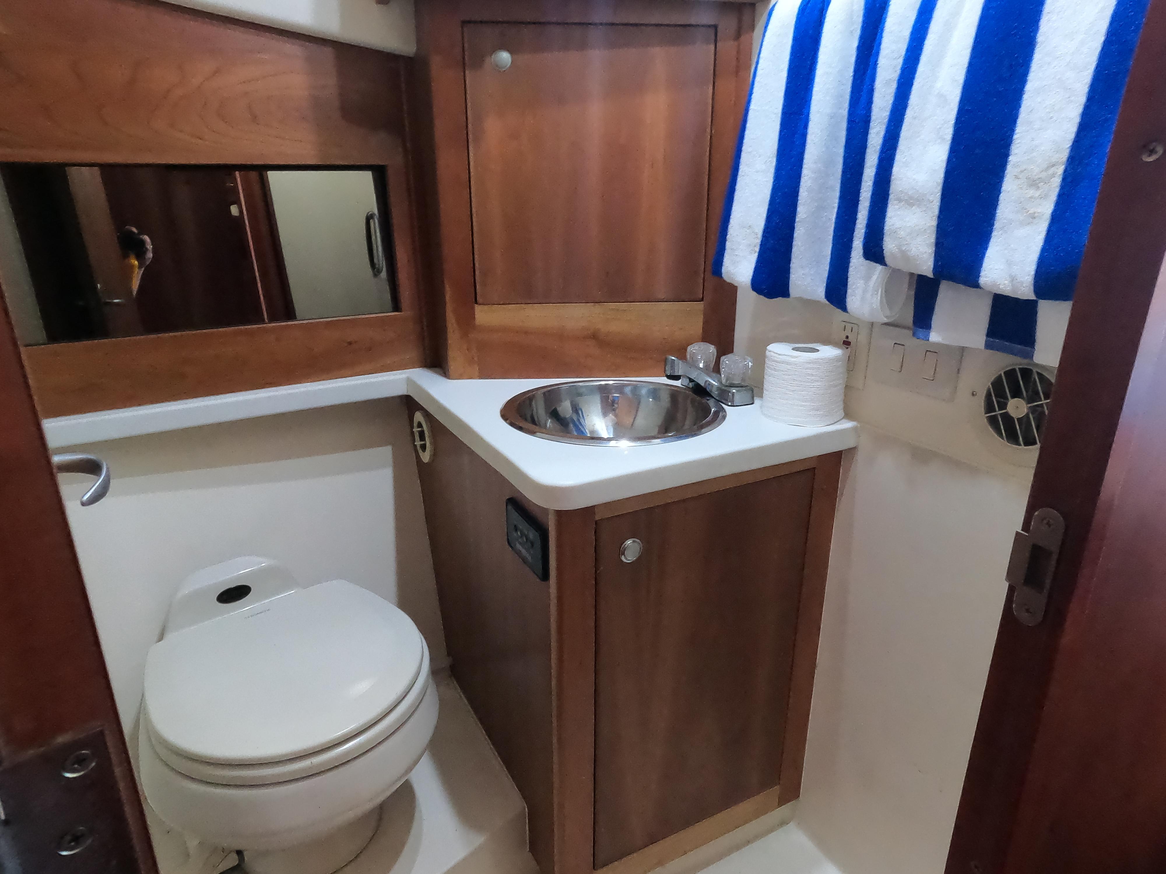 2002 Luhrs 34 Convertible boat bathroom with sink, toilet, and striped towel.