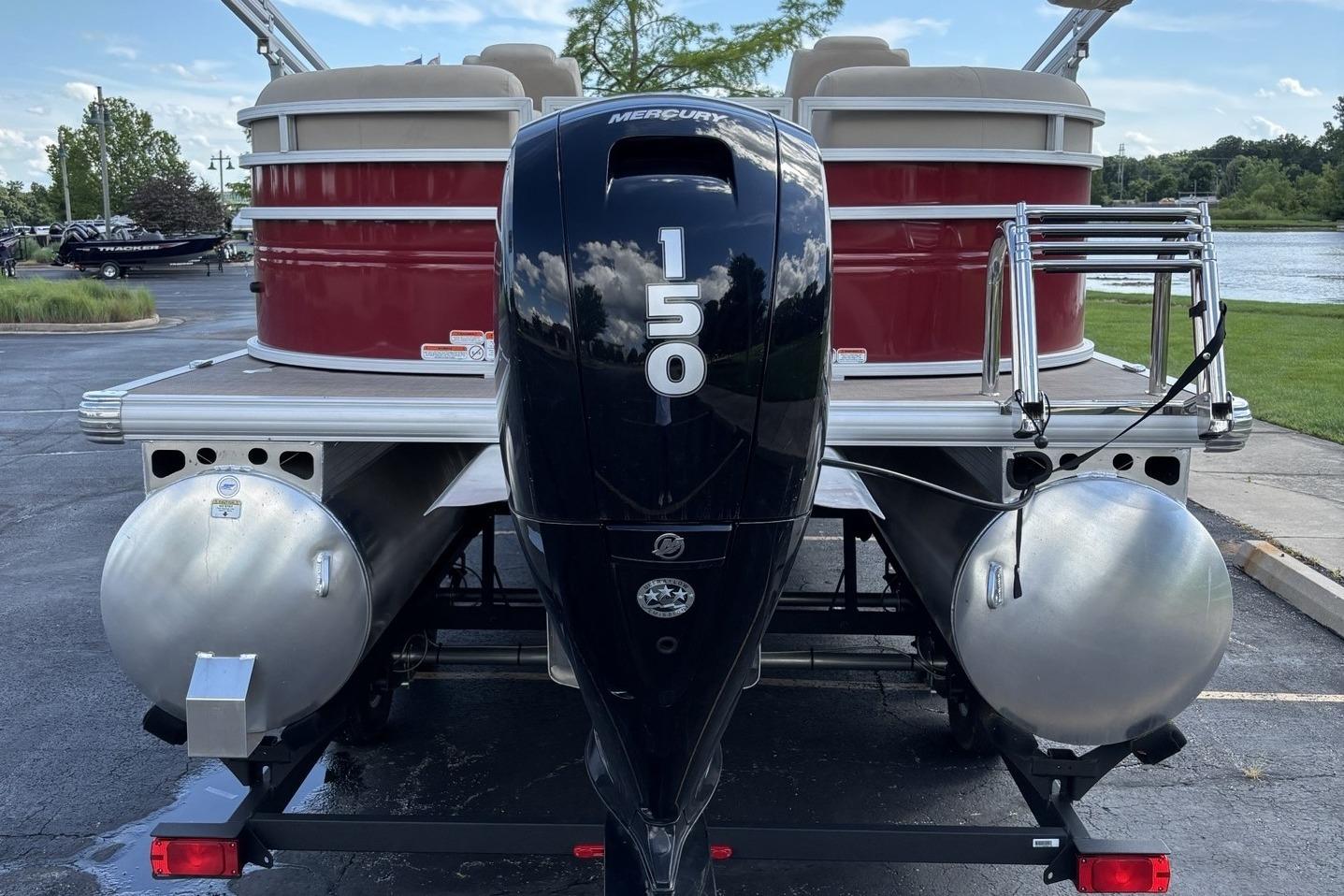 2024 Sun Tracker Party Barge 24 DLX with Mercury 150 engine, parked near a lake.
