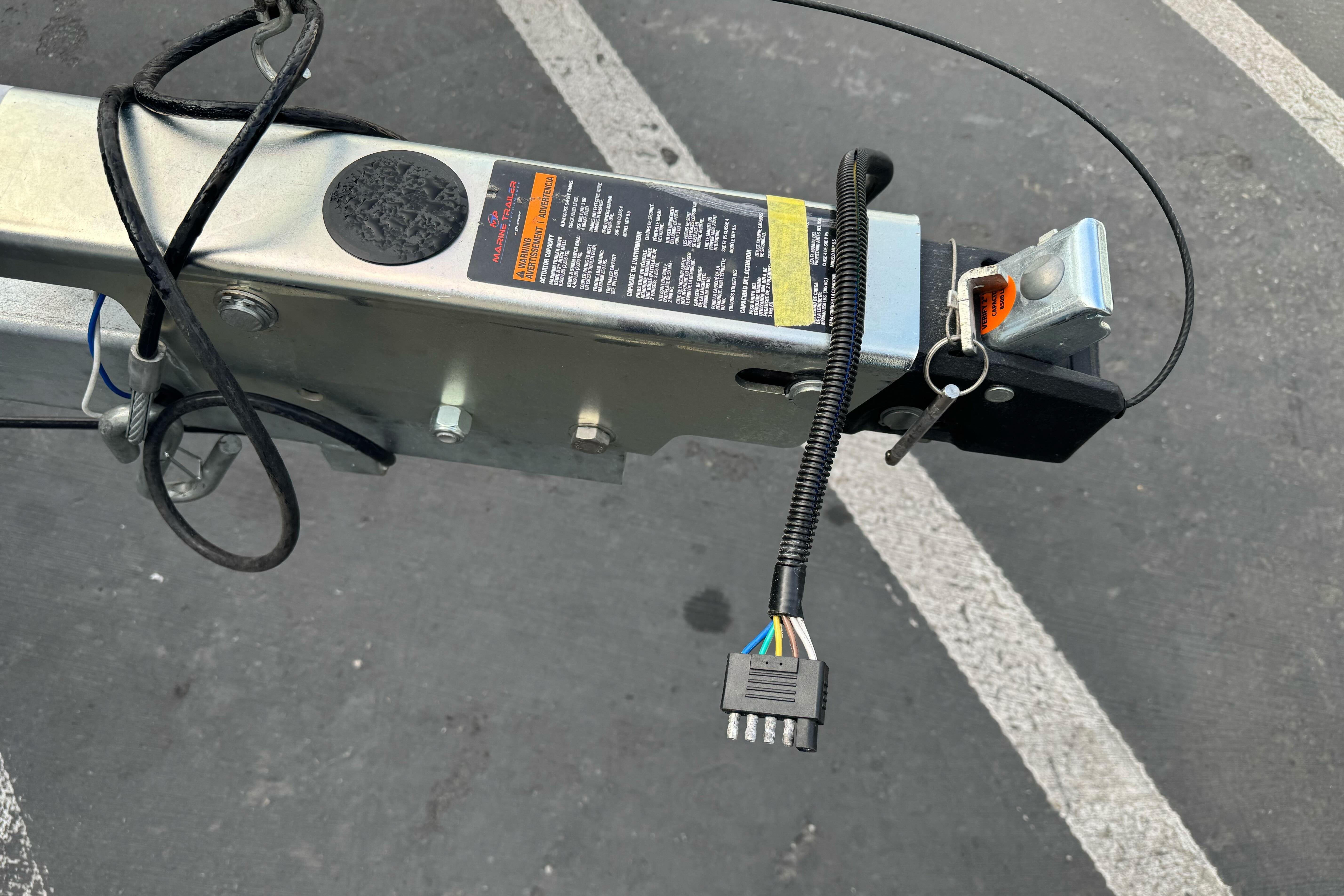 Trailer hitch and wiring of KingFisher 2025 Escape, 2026 model, in a parking lot.