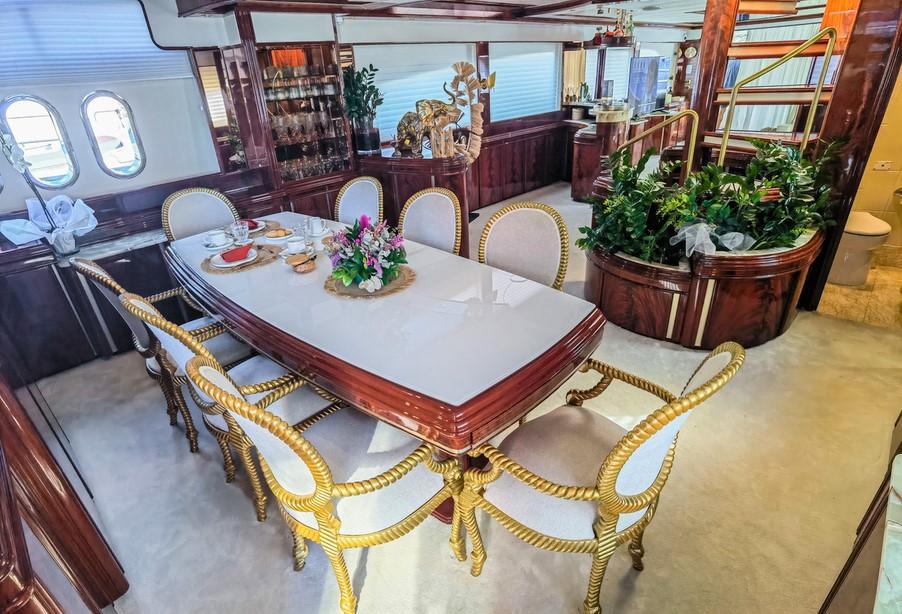 Luxurious dining area on 1997 Astondoa 95 GLX yacht with elegant decor and spiral staircase.