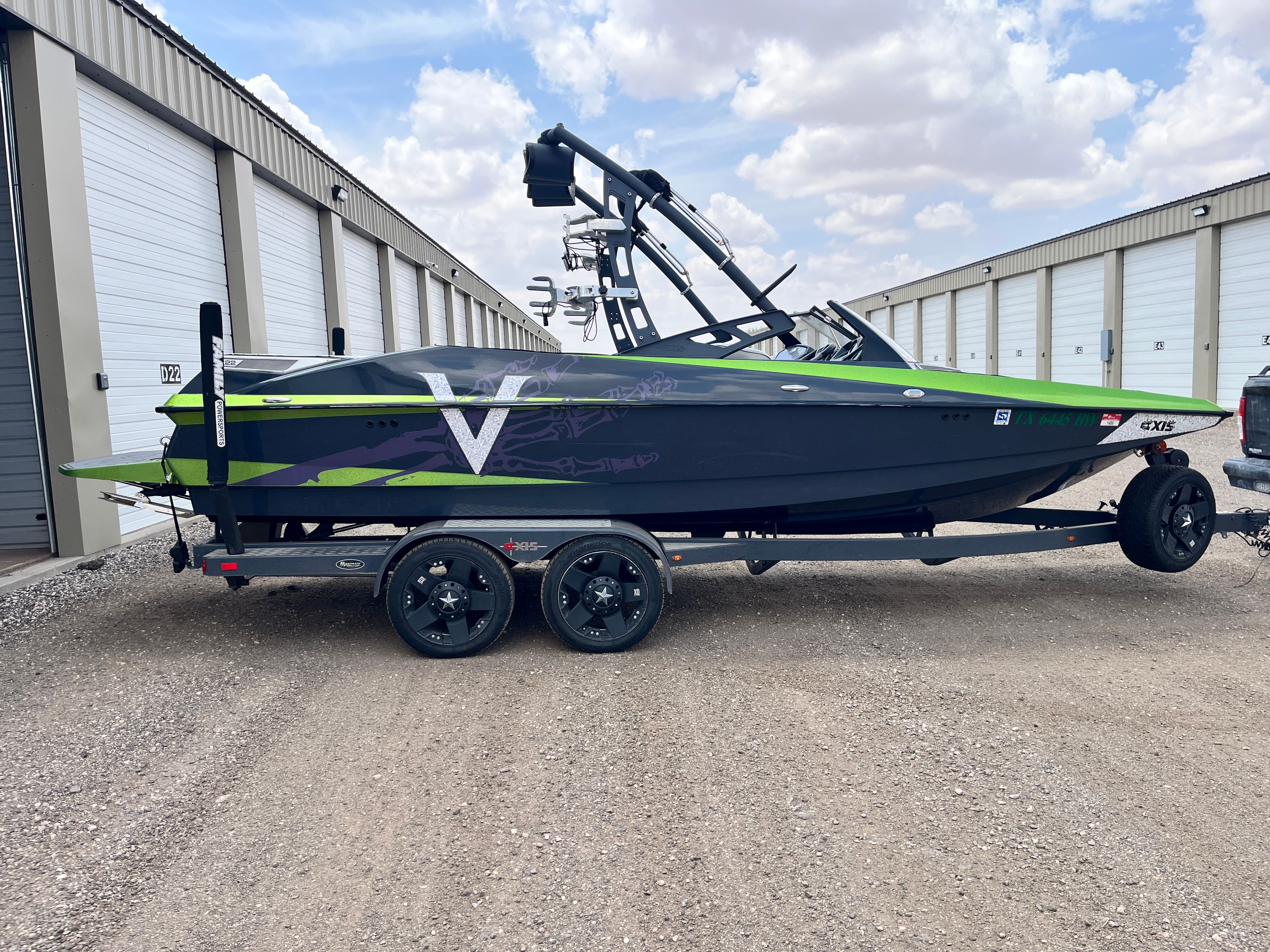 2013 Axis A22 boat on trailer in front of storage buildings.
