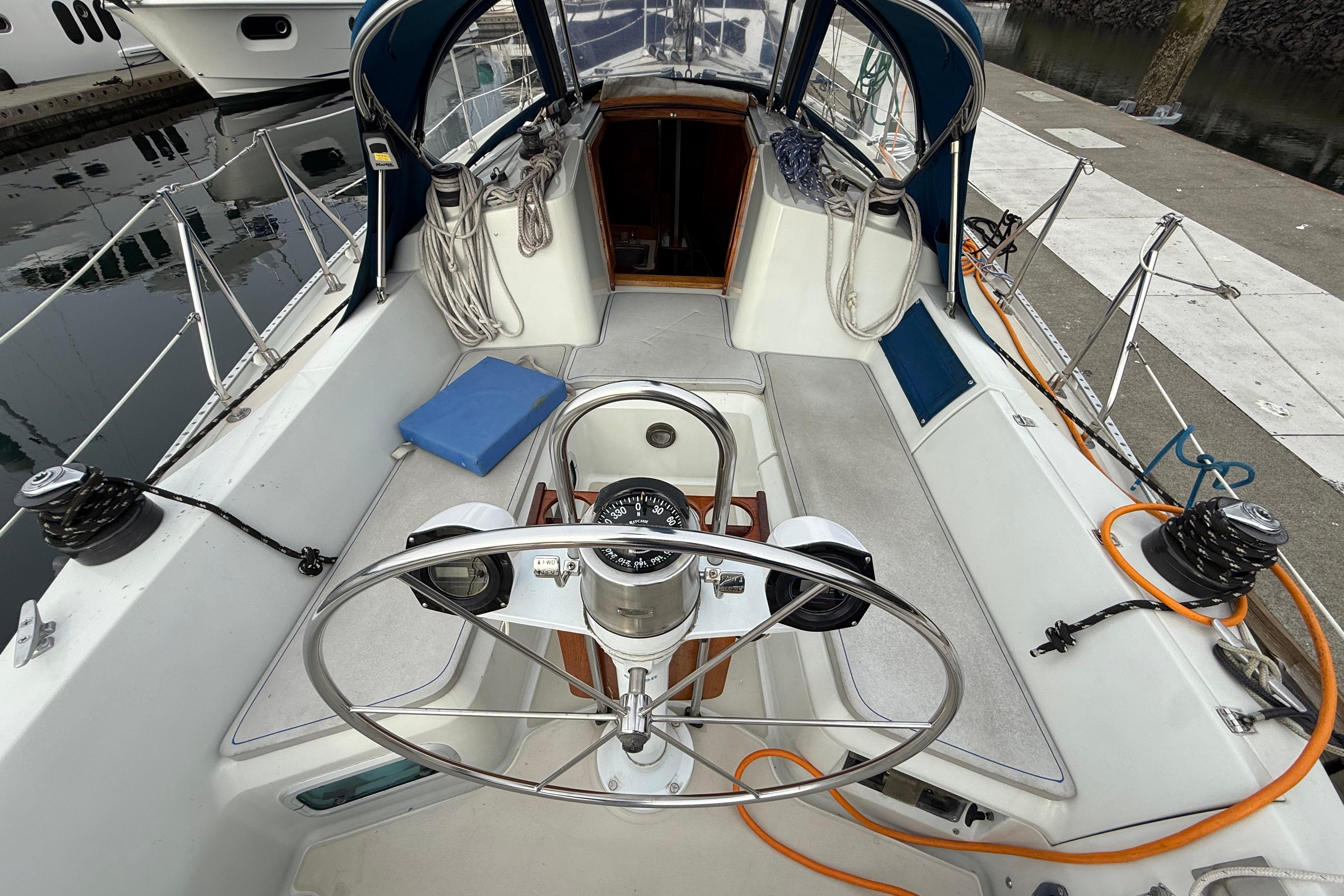 Cockpit of 1988 Ericson 32-200 sailboat with steering wheel and nautical equipment.
