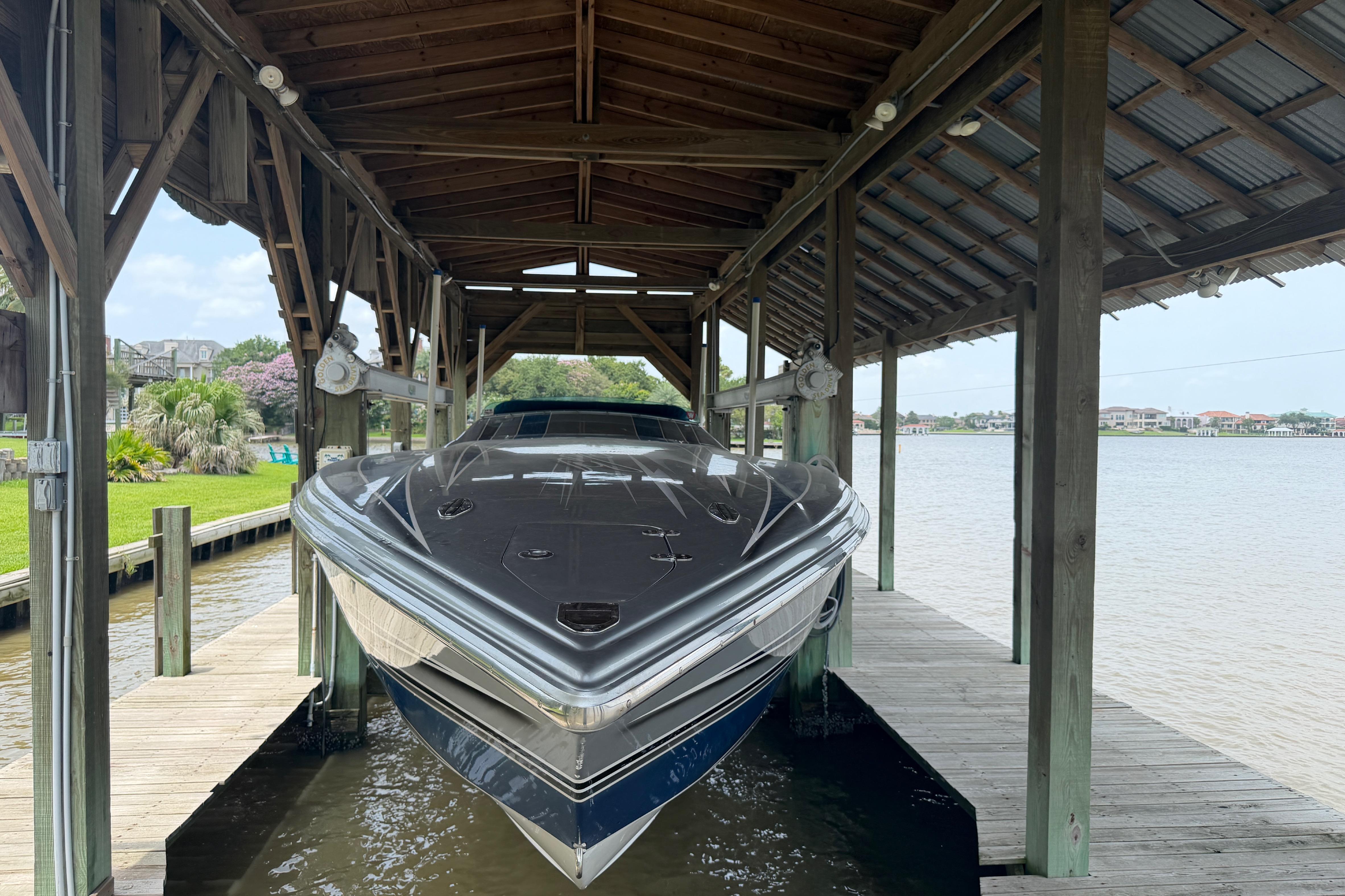 2013 Nor-Tech 477 SPX Vee Bottom boat docked under wooden shelter by the water.