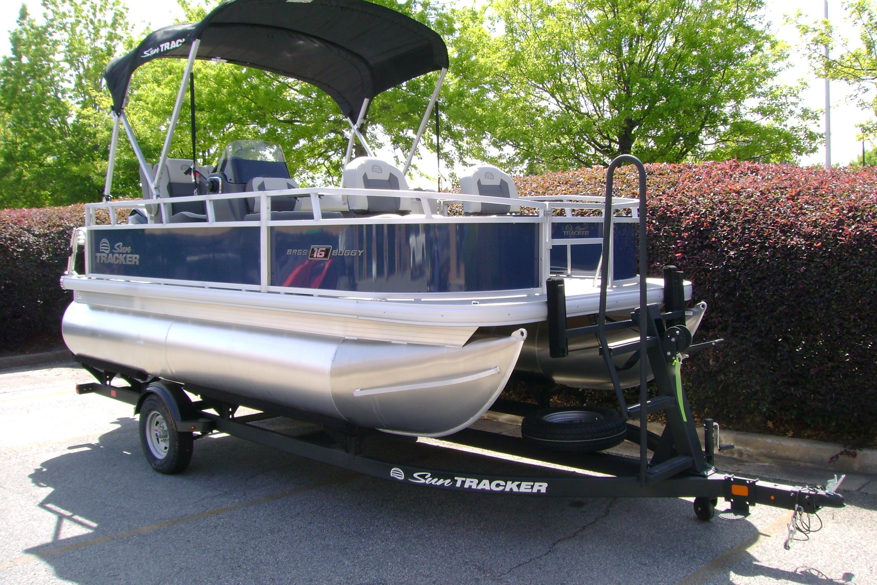 2026 Sun Tracker Bass Buggy 16 XL Select pontoon boat on trailer, parked outdoors.