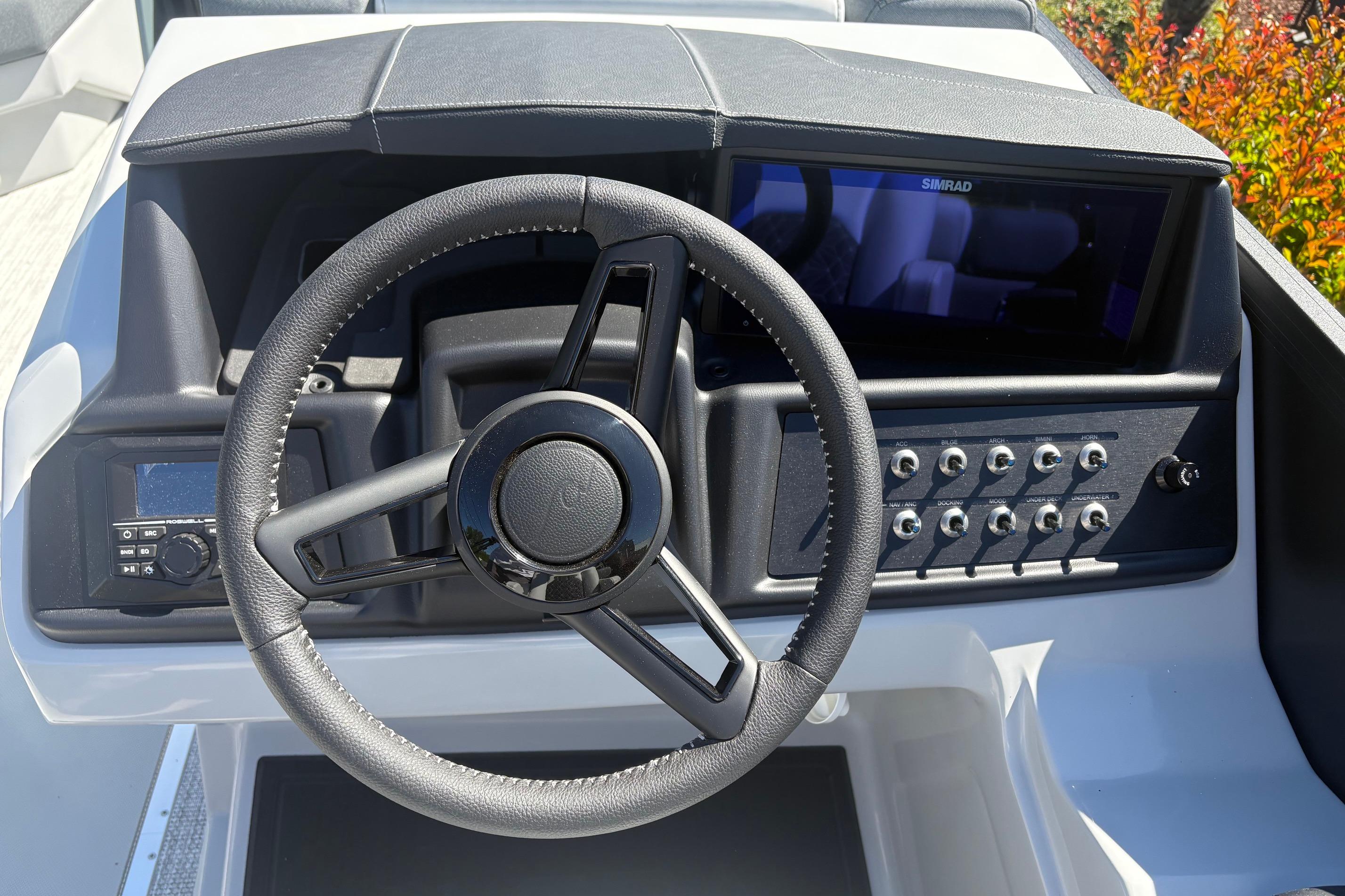 Steering wheel and dashboard of 2026 Alera 23Q boat with control panel and display.