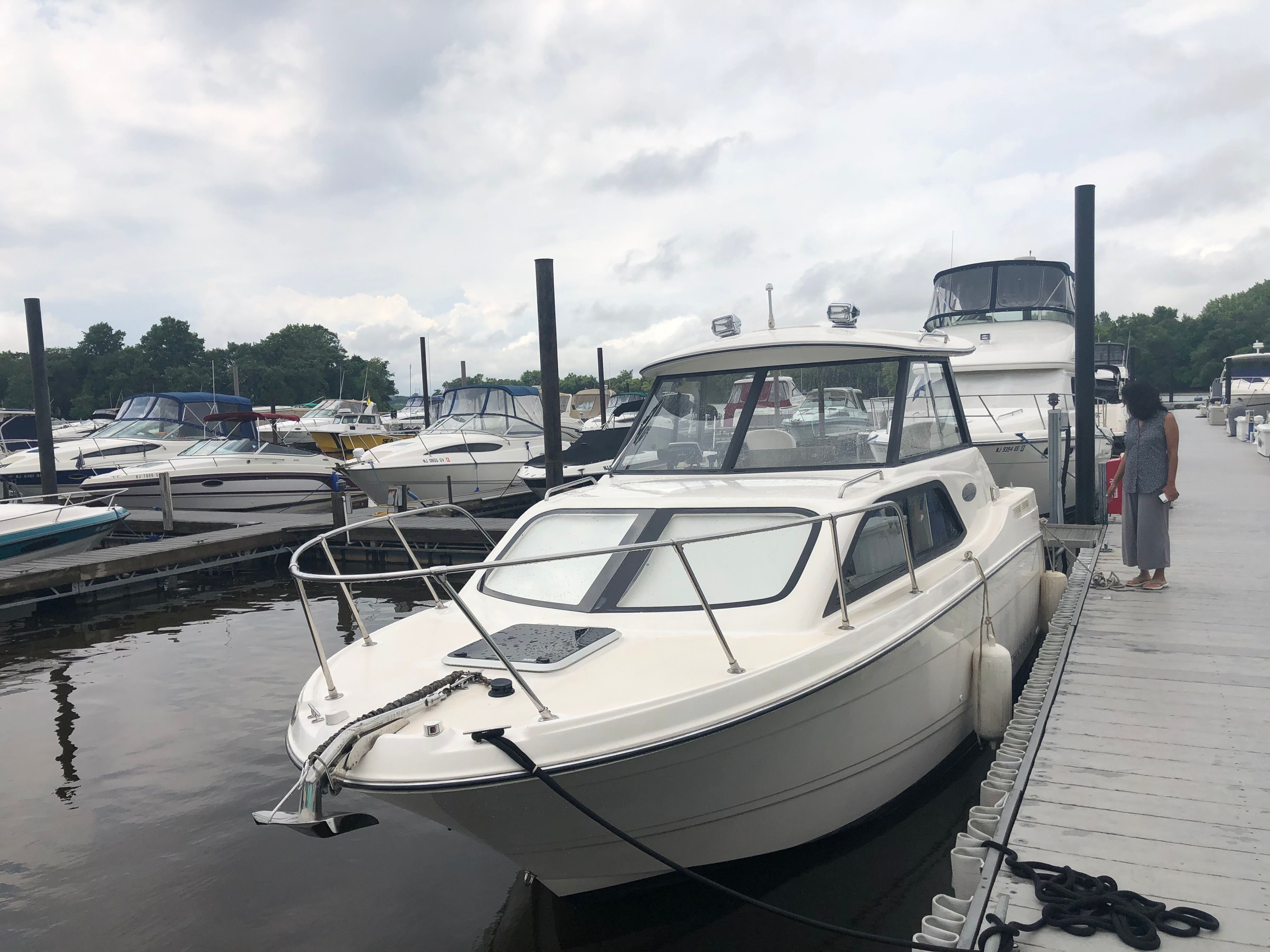 2003 Bayliner 2452 Classic Cruiser docked under cloudy skies.