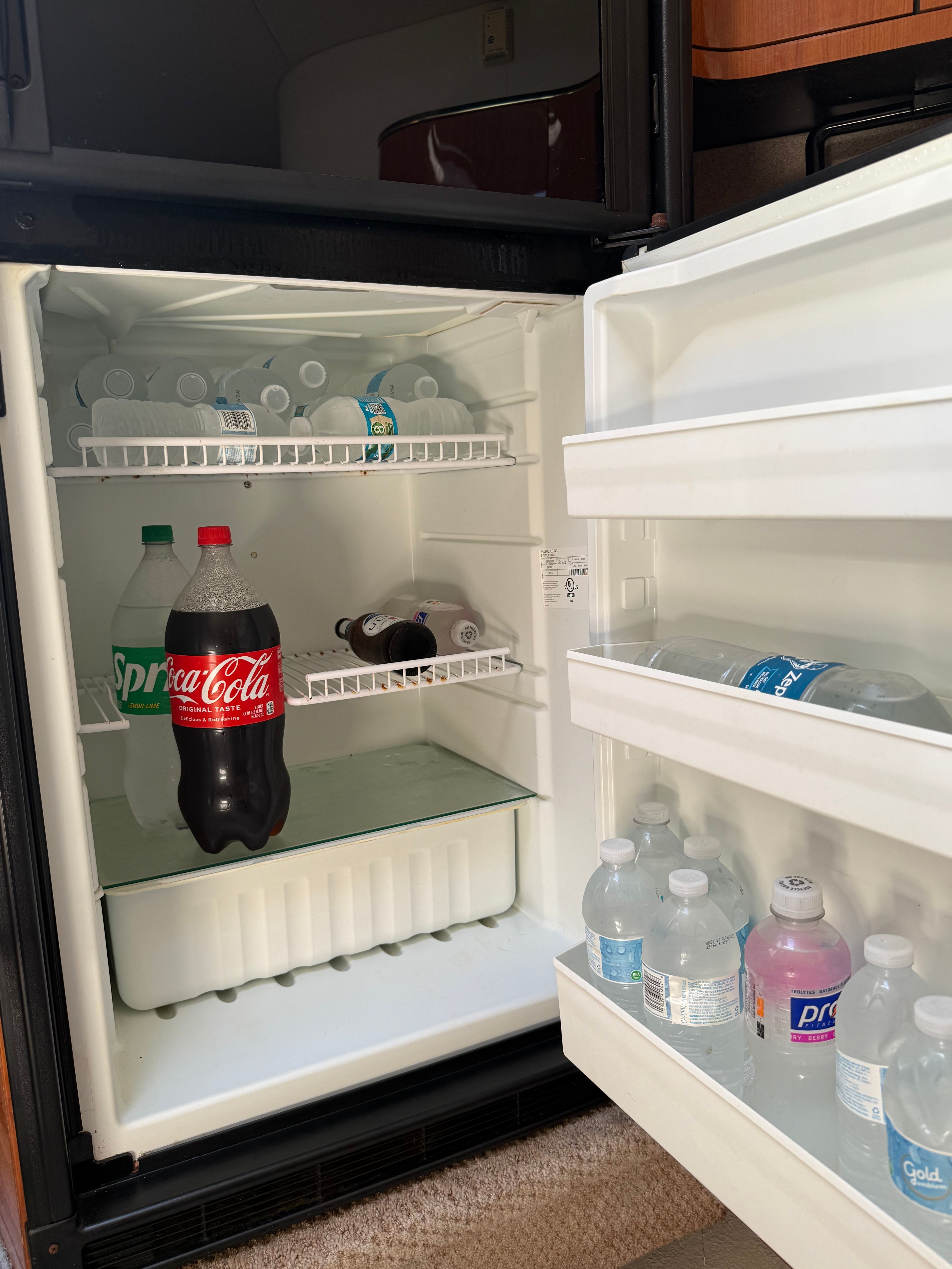 An open fridge on a boat with drinks and water bottles.