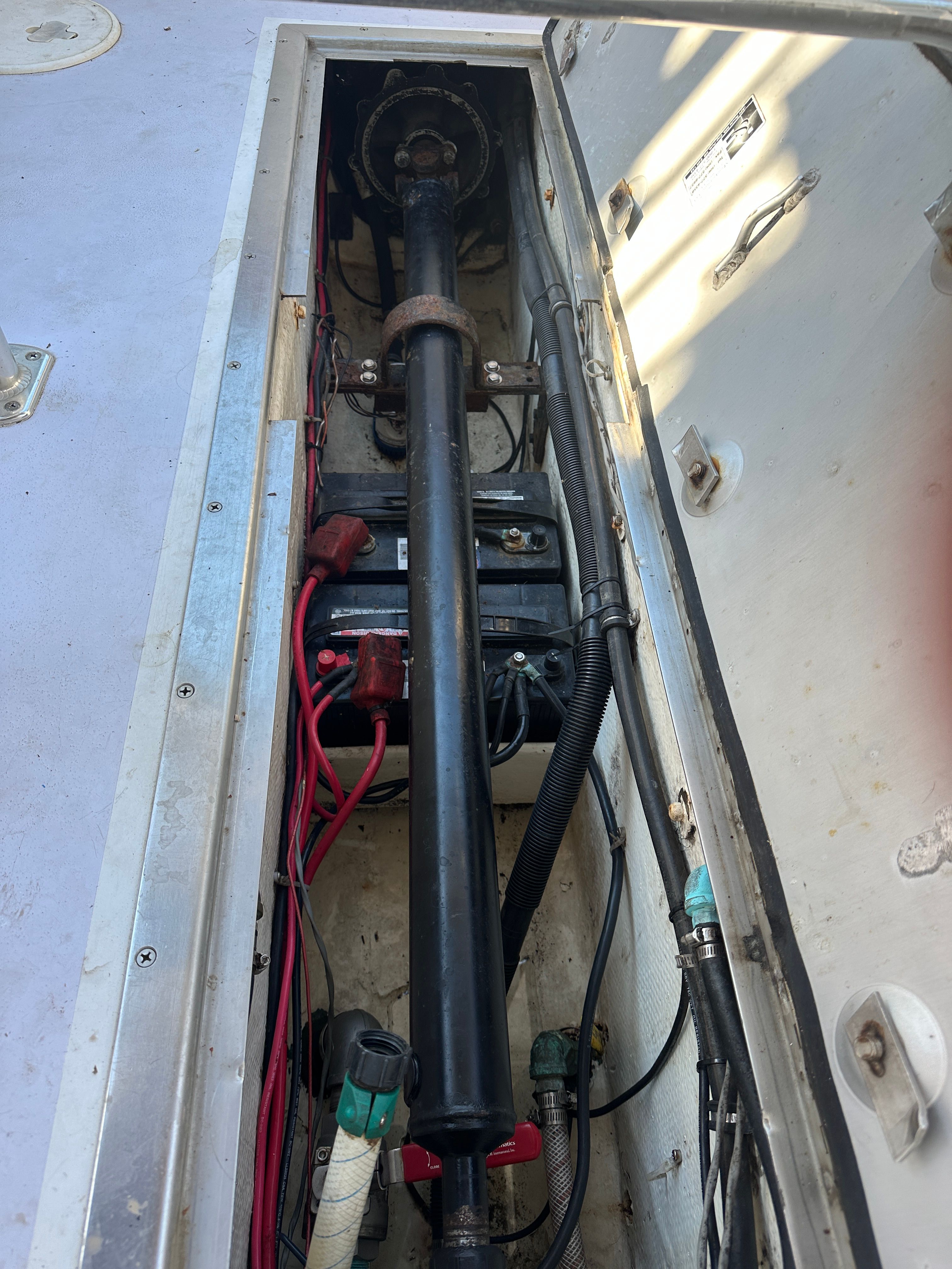 A view inside the engine compartment of a 1976 Blackfin Fisherman boat with batteries and cables.