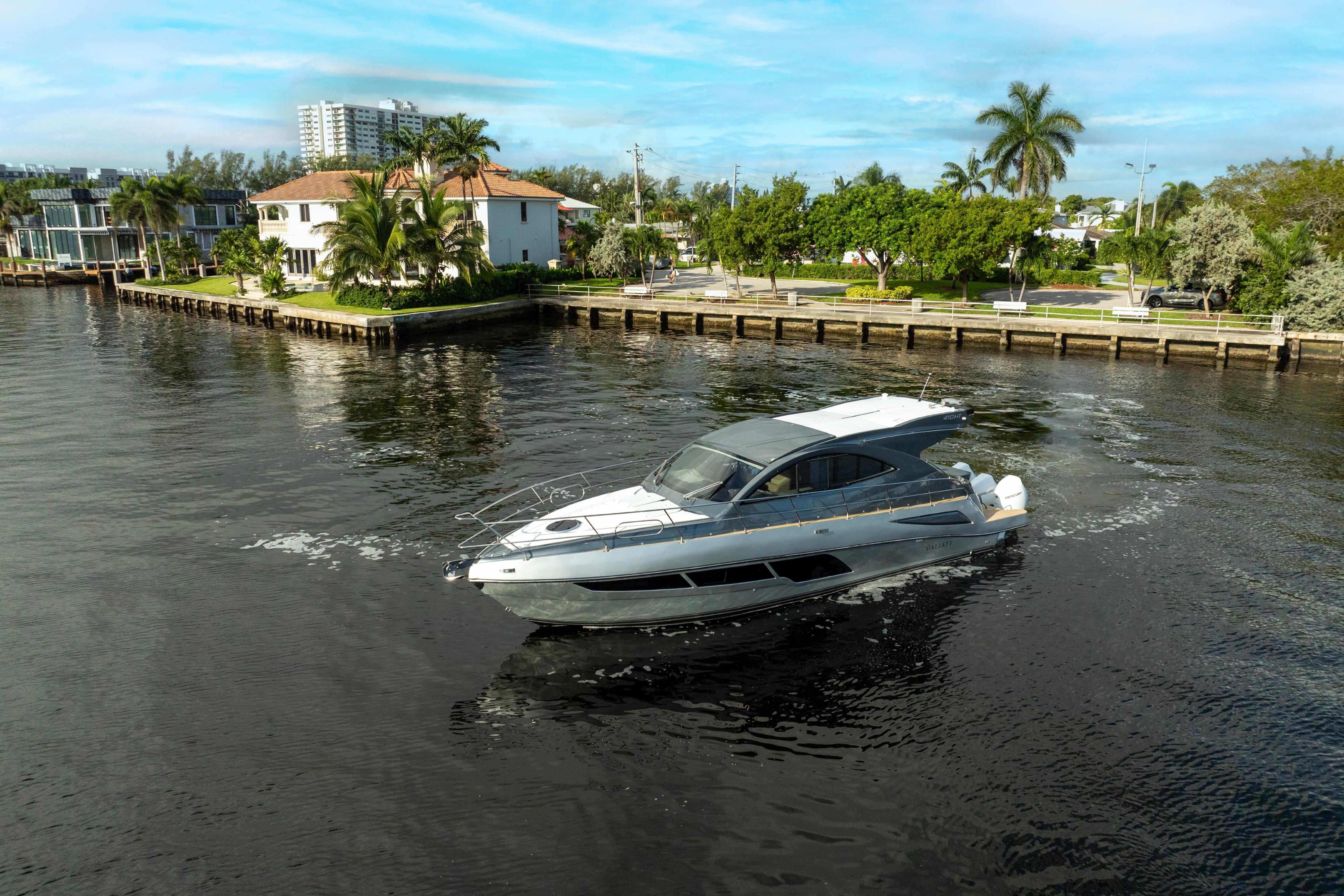 2025 Valiatt 410HT luxury yacht cruising near waterfront homes, surrounded by lush greenery.