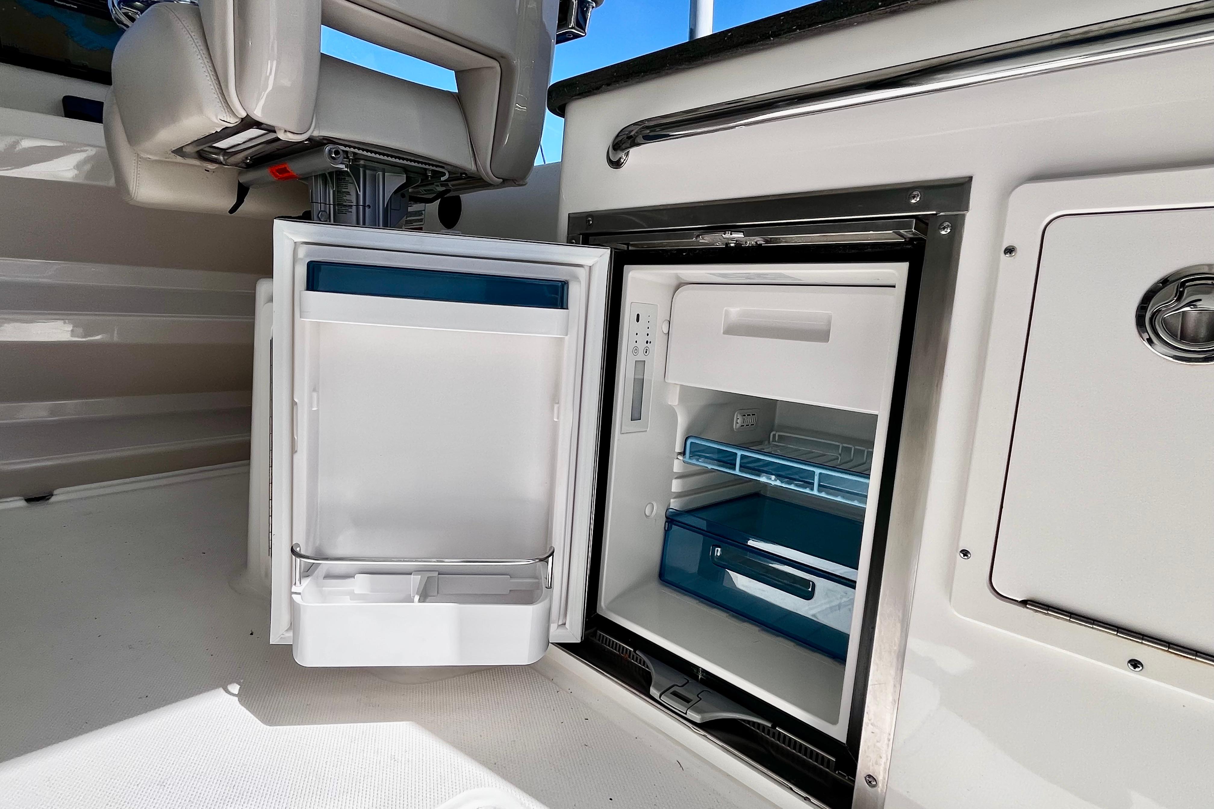 Open refrigerator on 2026 Boston Whaler 325 Conquest Pilothouse boat, showcasing interior storage.