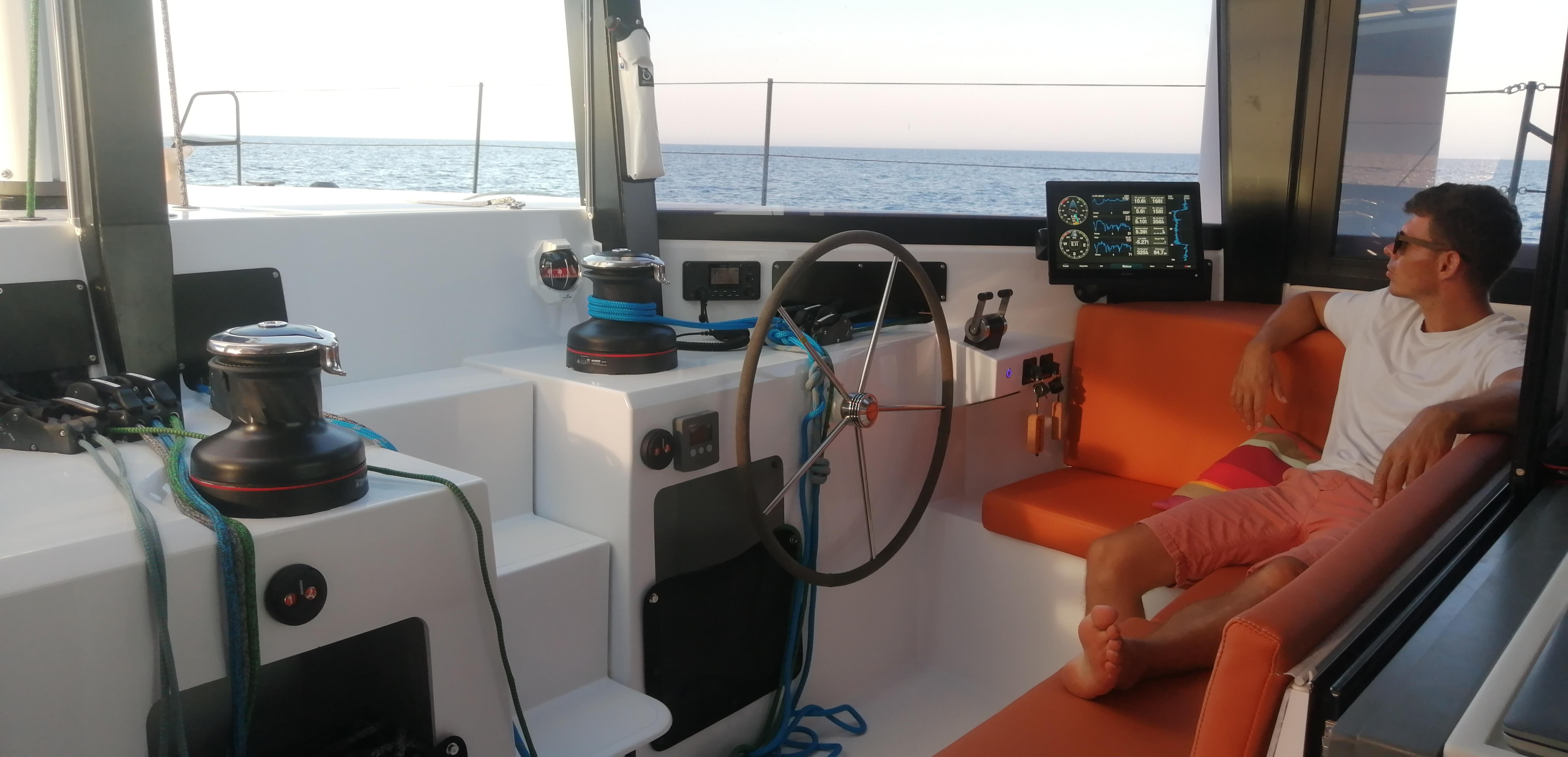 Interior of 2025 Windelo 50 Adventure yacht with man relaxing on orange seating.