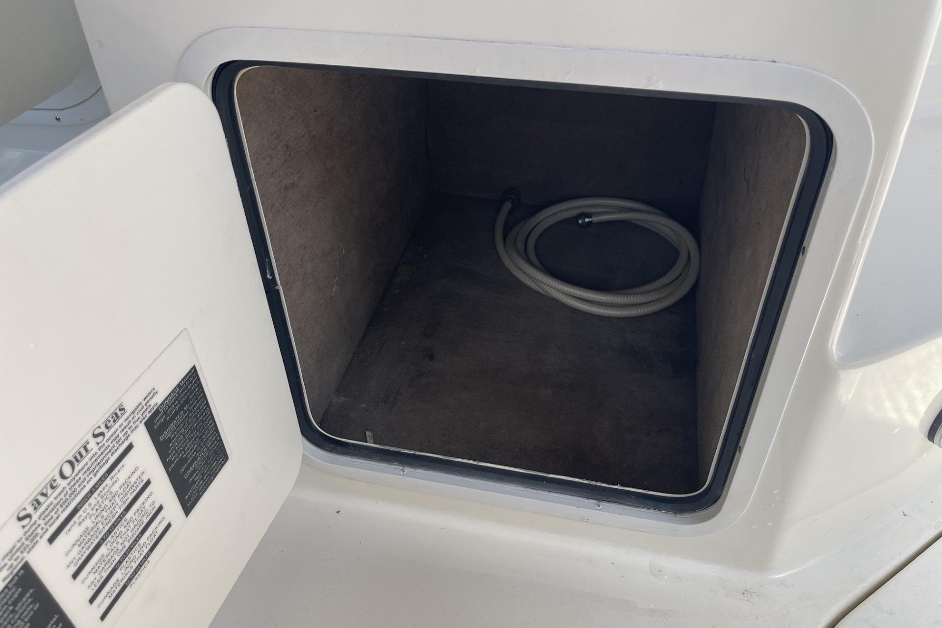 Open storage compartment on a 2000 Sea Ray Sundancer 260 boat, featuring a coiled hose.